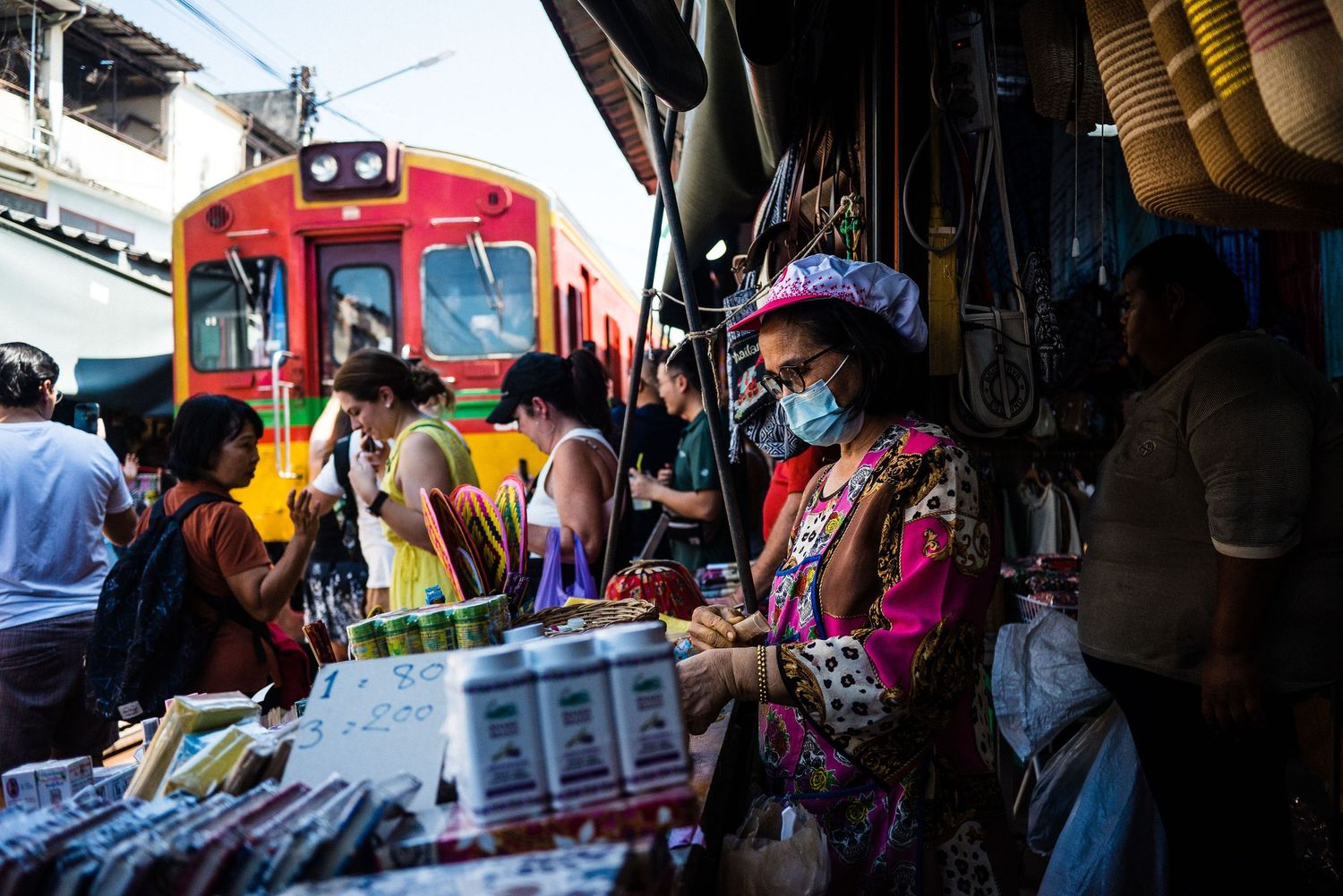 Bustling street market scene with colorful train and vendors selling goods.