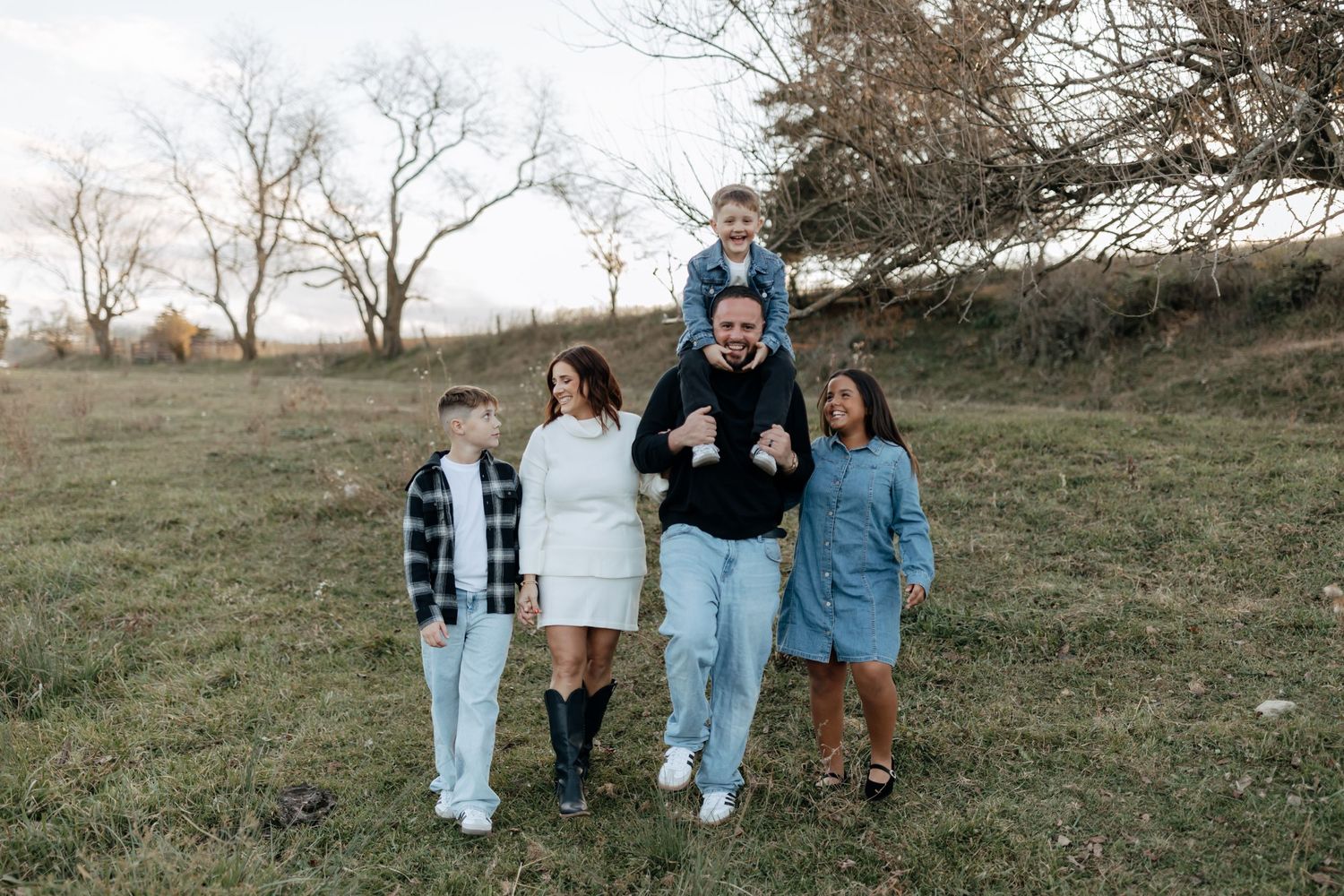 Family group walking together on hillside during casual outdoor photo session.