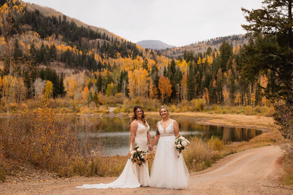 A scenic fall wedding by a mountain lake surrounded by golden aspen trees and evergreens in autumn.