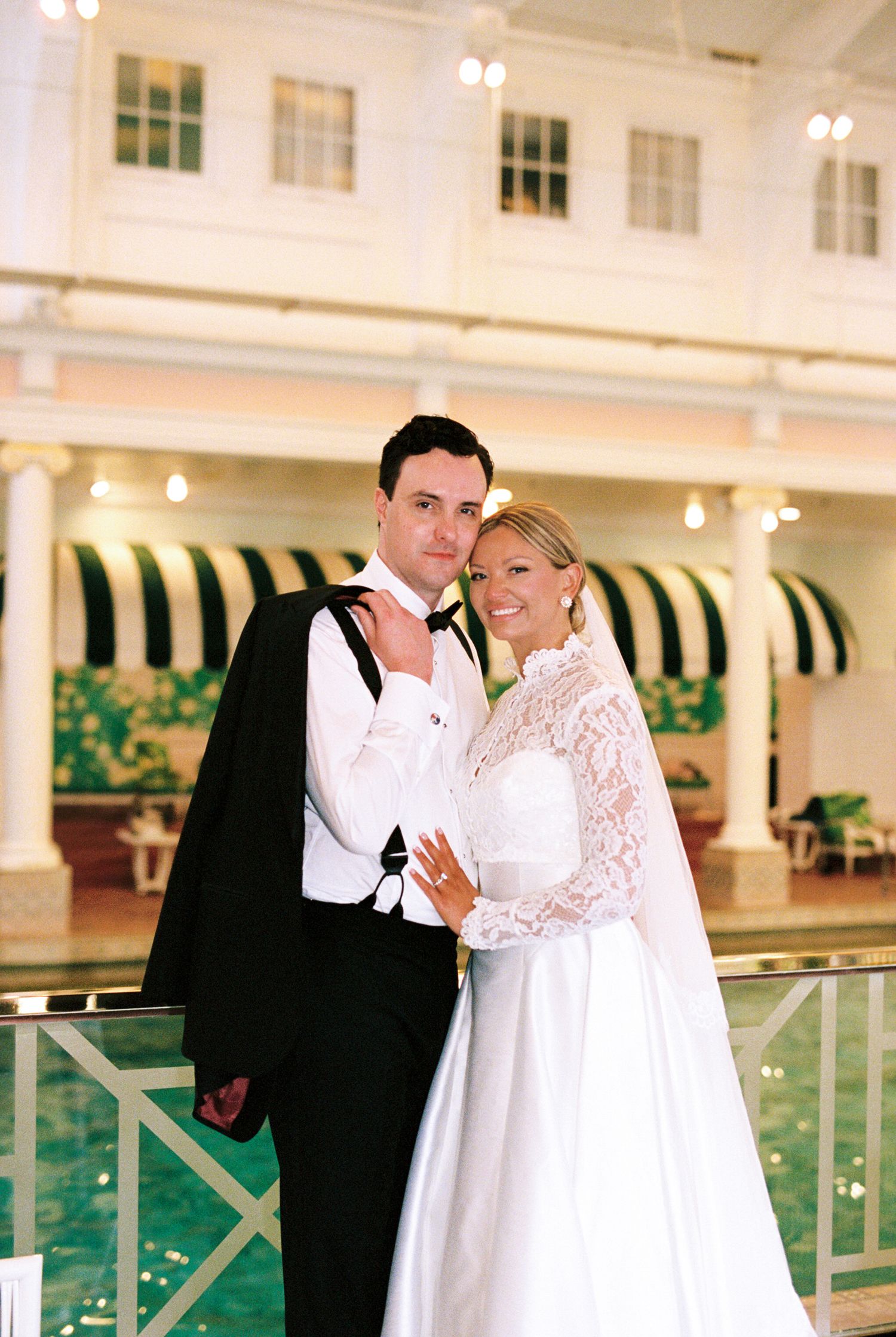 A wedding ceremony in a wooded setting with white draped fabric decor and a Persian rug aisle runner.