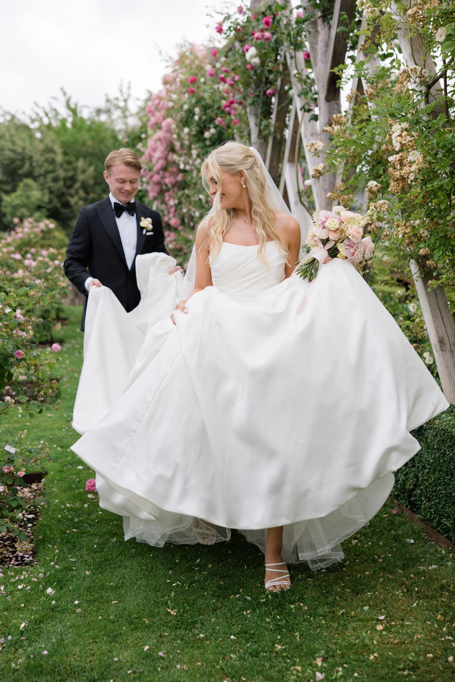 Wedding party holding white parasols in a garden with bridesmaids in mint green dresses.