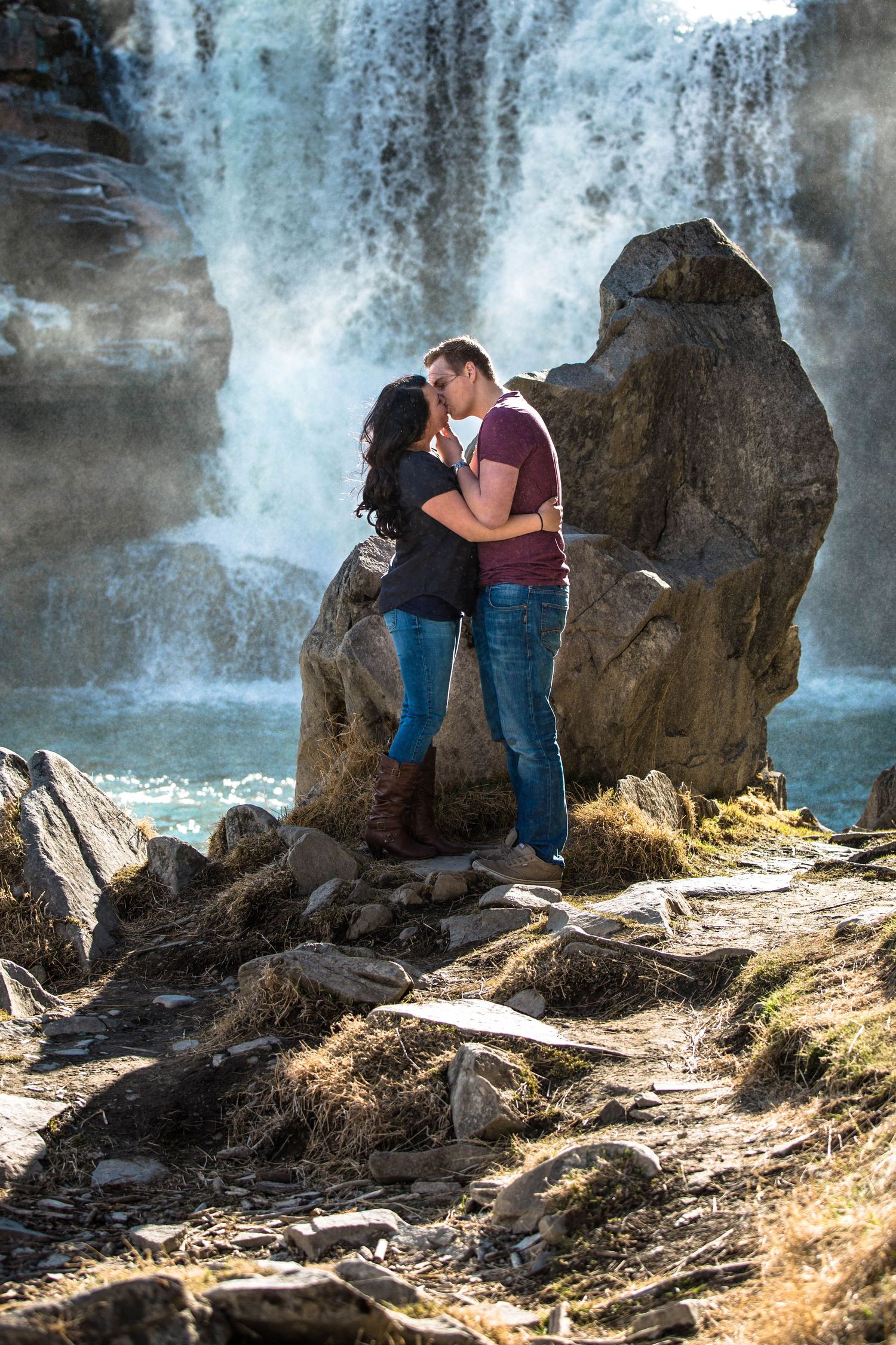 Romantic moment captured by waterfall with dramatic rocks and mist.