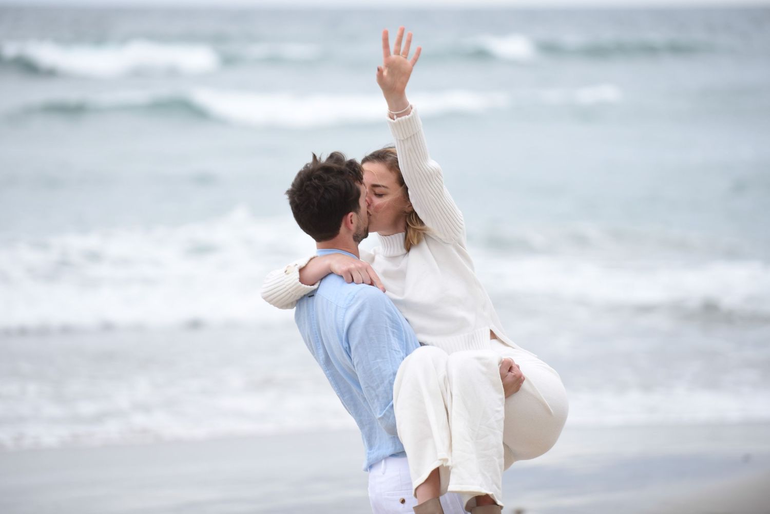 Romantic seaside proposal photos showing the couple's celebration against ocean waves.