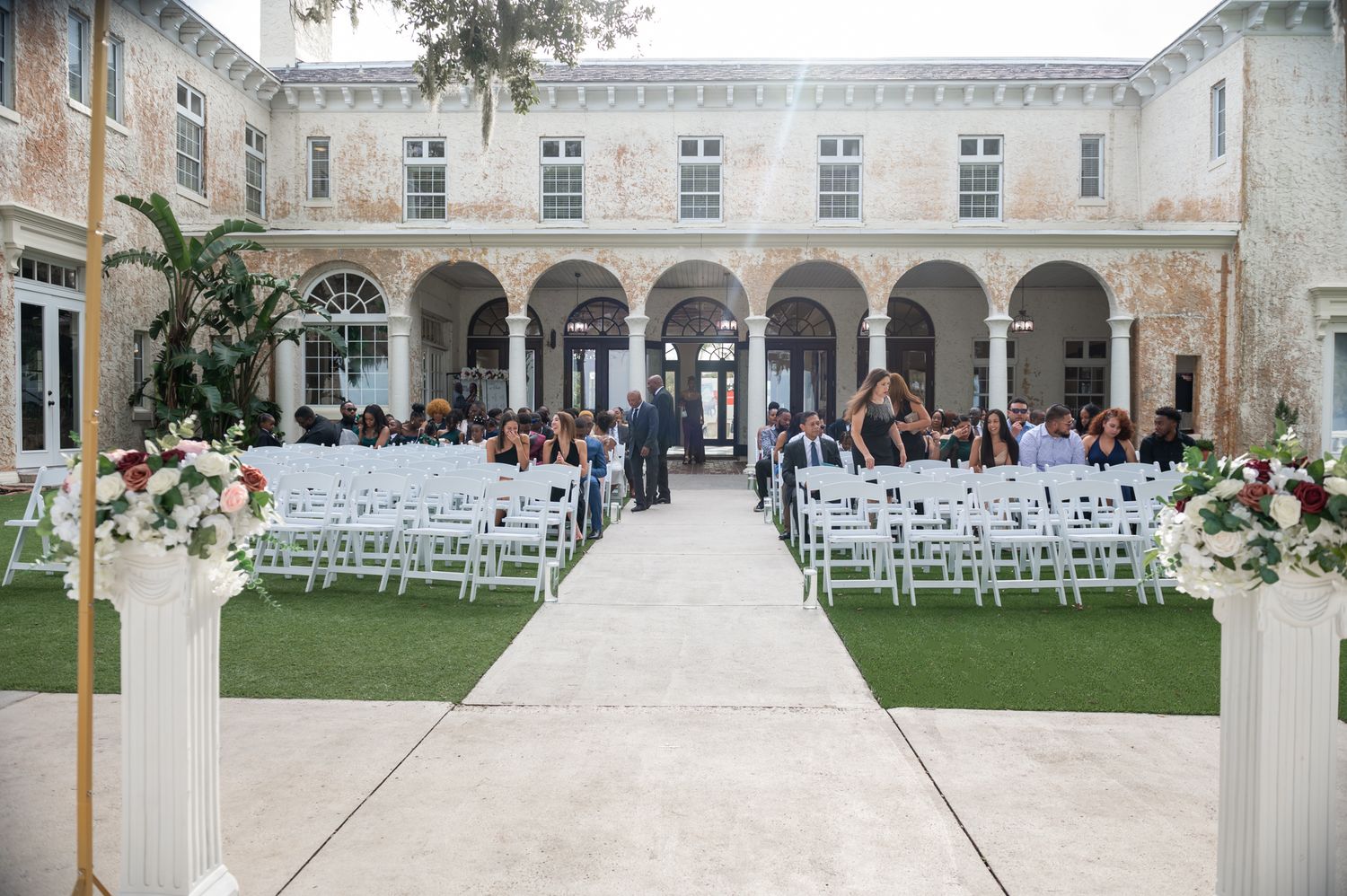 Bride and groom walking beneath Spanish arches at Bella Cosa, captured by Lake Wales wedding photographers in golden light.