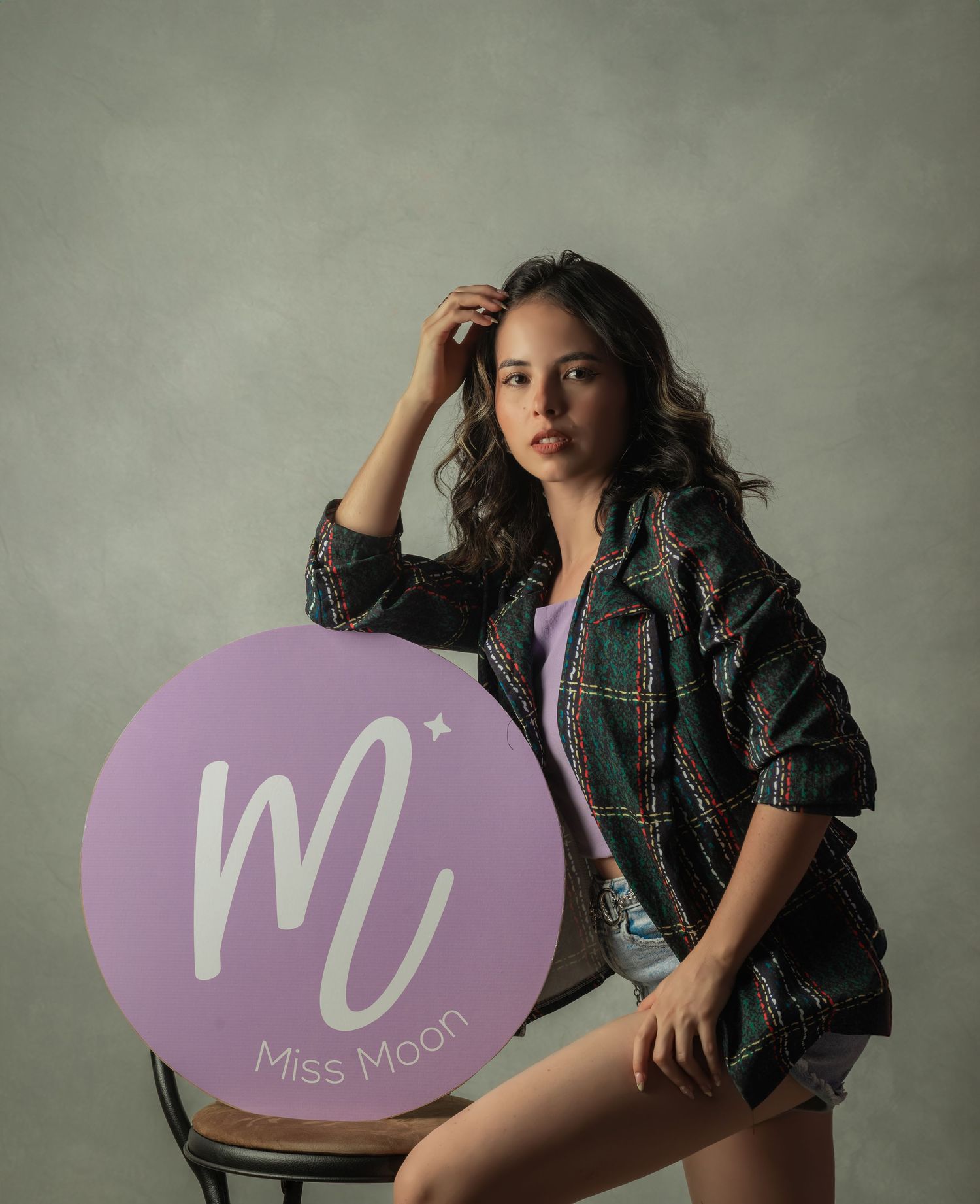 Artistic brand photoshoot with purple Miss Moon logo circle prop and stylish outfit.
