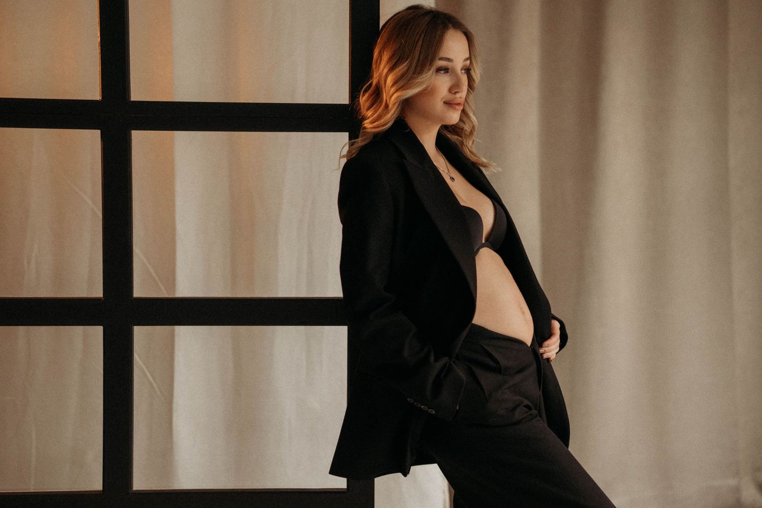 Solo maternity photoshoot in a studio – pregnant woman in a black men's suit.