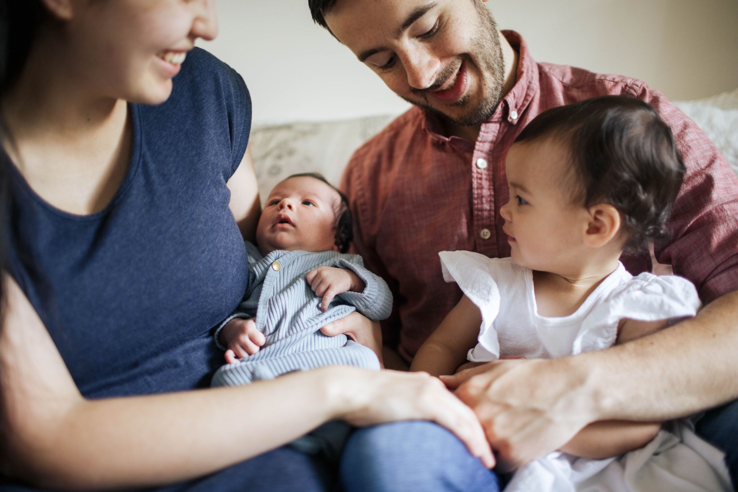 Everett lifestyle newborn photographer: A family of 4 sit on the bed during their newborn photo shoot at home in Everett WA