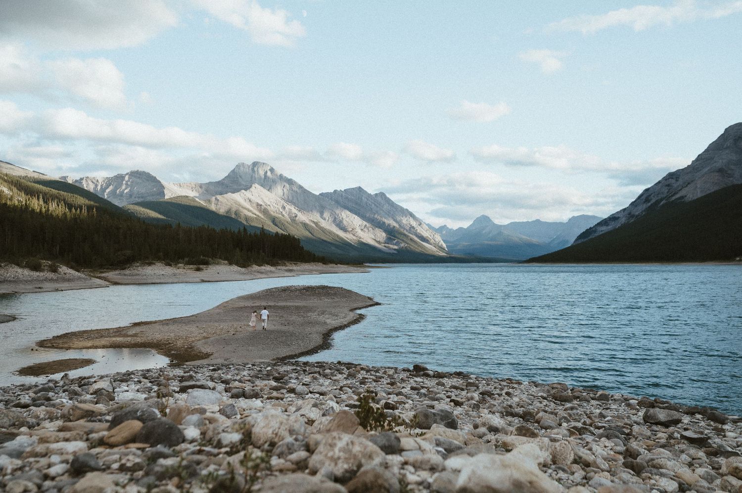 Majestic mountain lake landscape with rocky shoreline and snow-capped peaks in the distance.