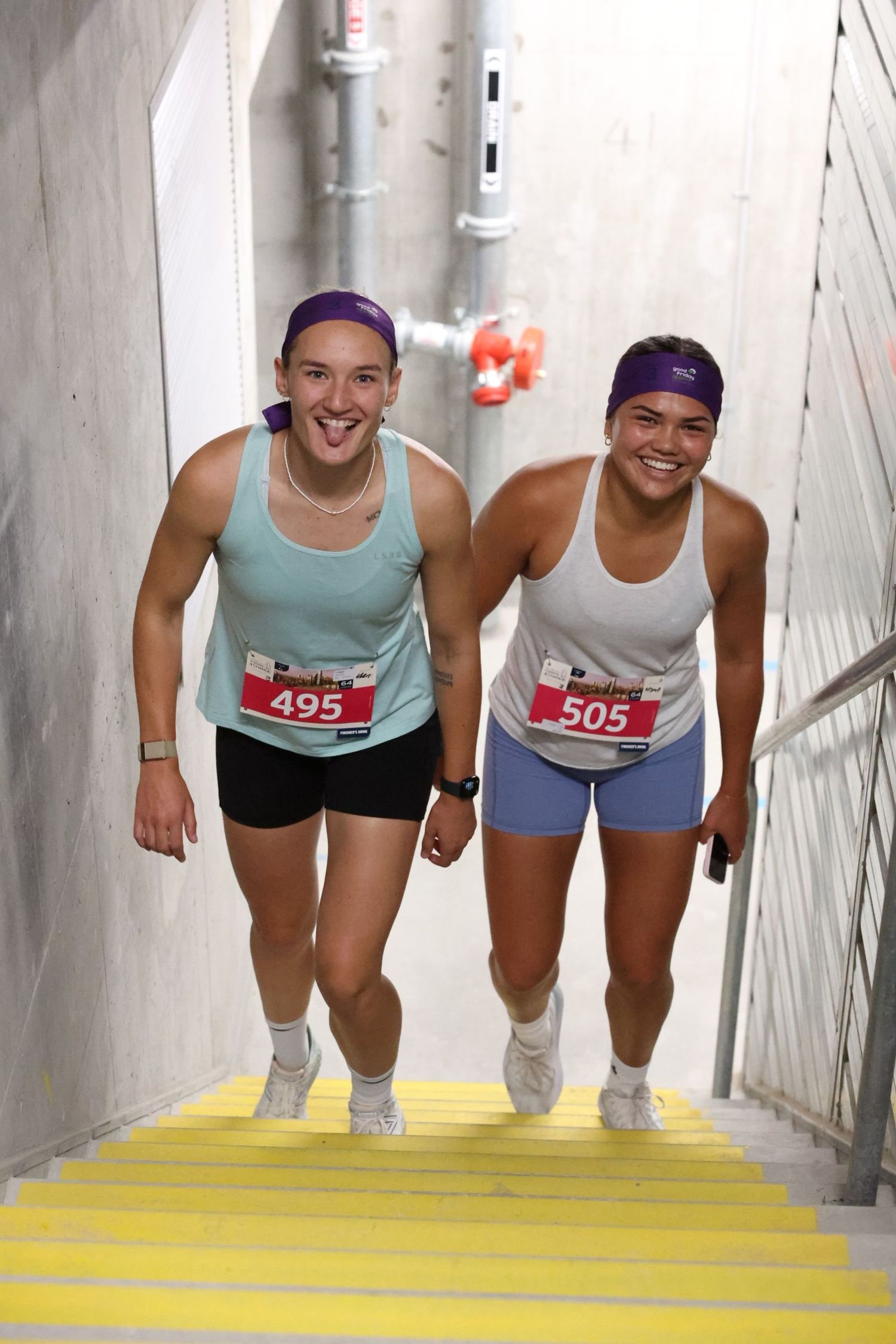 Two race participants climbing yellow stairs during athletic event.