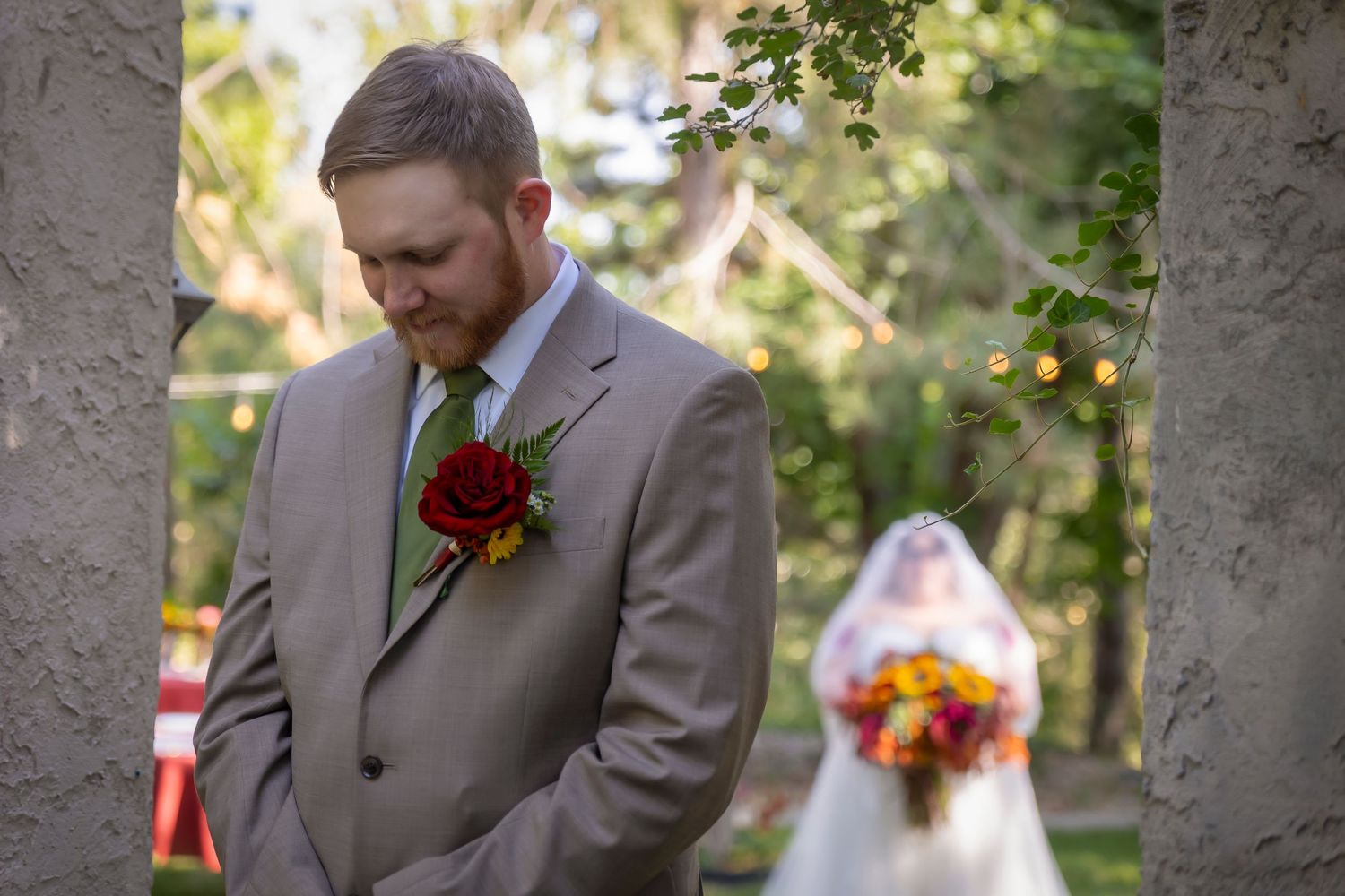 first look groom looking down and bride in the distance