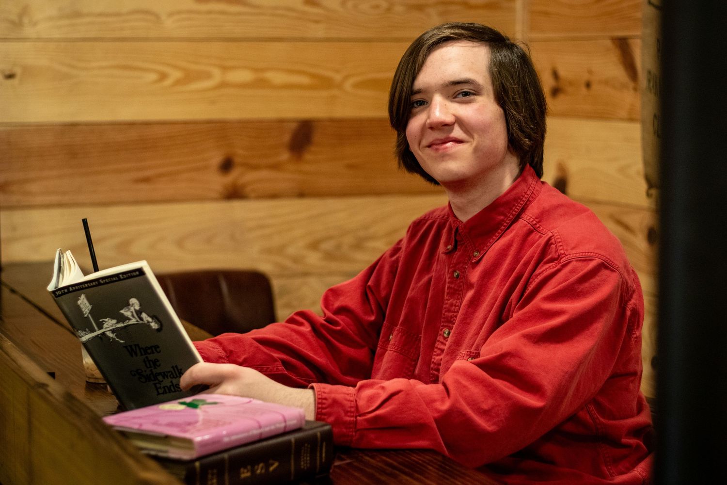 A young man senior session at a coffee shop with his favorite childhood books.
