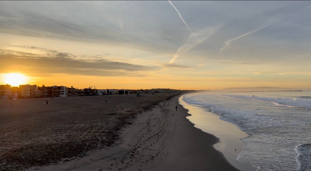 Scenic beach sunset view with waves crashing on shoreline and golden sky reflecting on wet sand.
