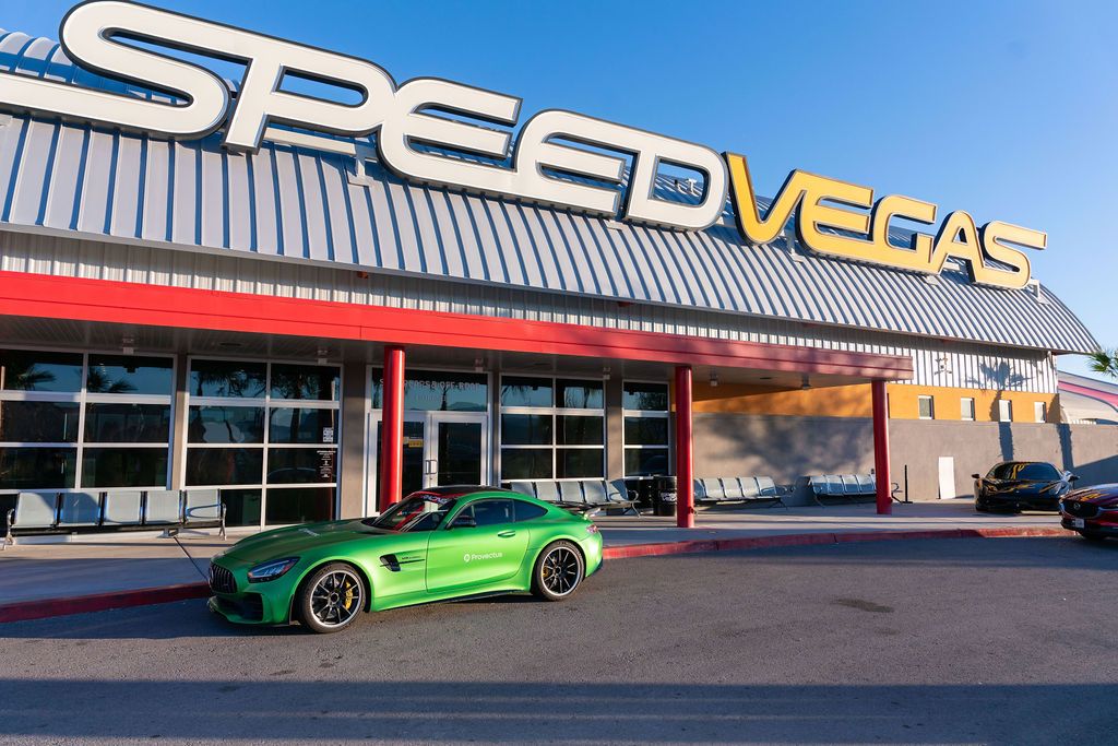 A vibrant green Mercedes-AMG GT sports car parked outside the SpeedVegas racing experience facility in Las Vegas.