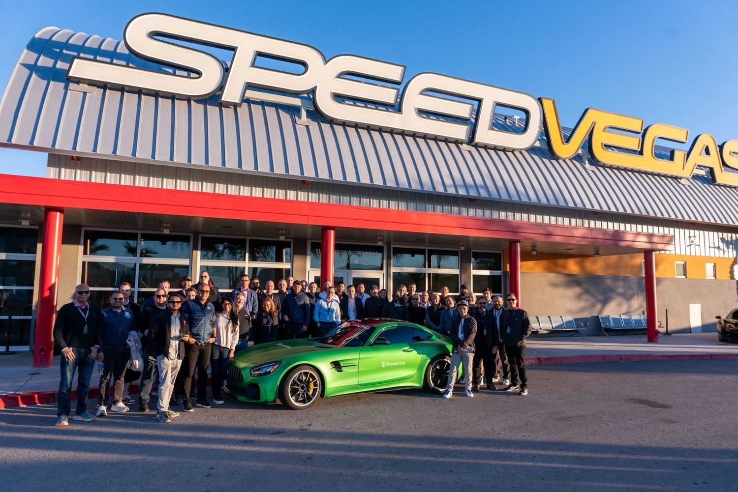 A vibrant green Mercedes-AMG GT sports car parked outside the SpeedVegas racing experience facility in Las Vegas.