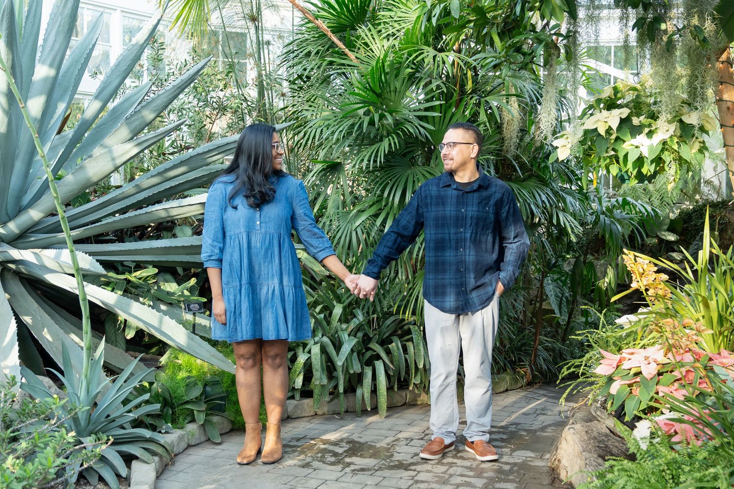 Couple walks through lush tropical garden with palm trees and exotic plants at botanical gardens.