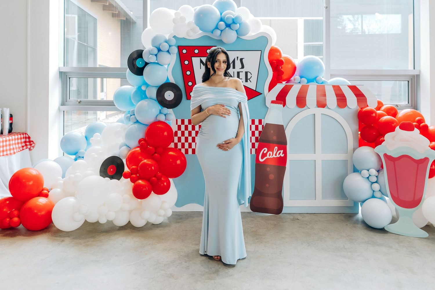 Red, white and blue balloon garland decorations create a retro diner theme party atmosphere along a wall.