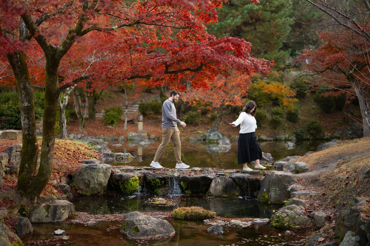 Couple standing together in a traditional Japanese garden with a historic pagoda-style building in the background.