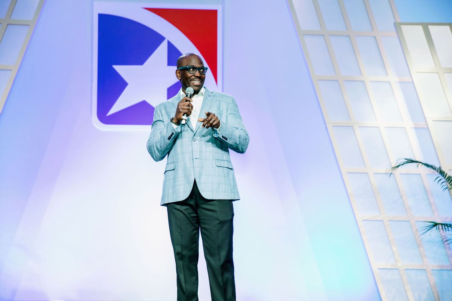 Man in blue suit speaking at podium with Tennessee state flag logo backdrop at formal conference event.