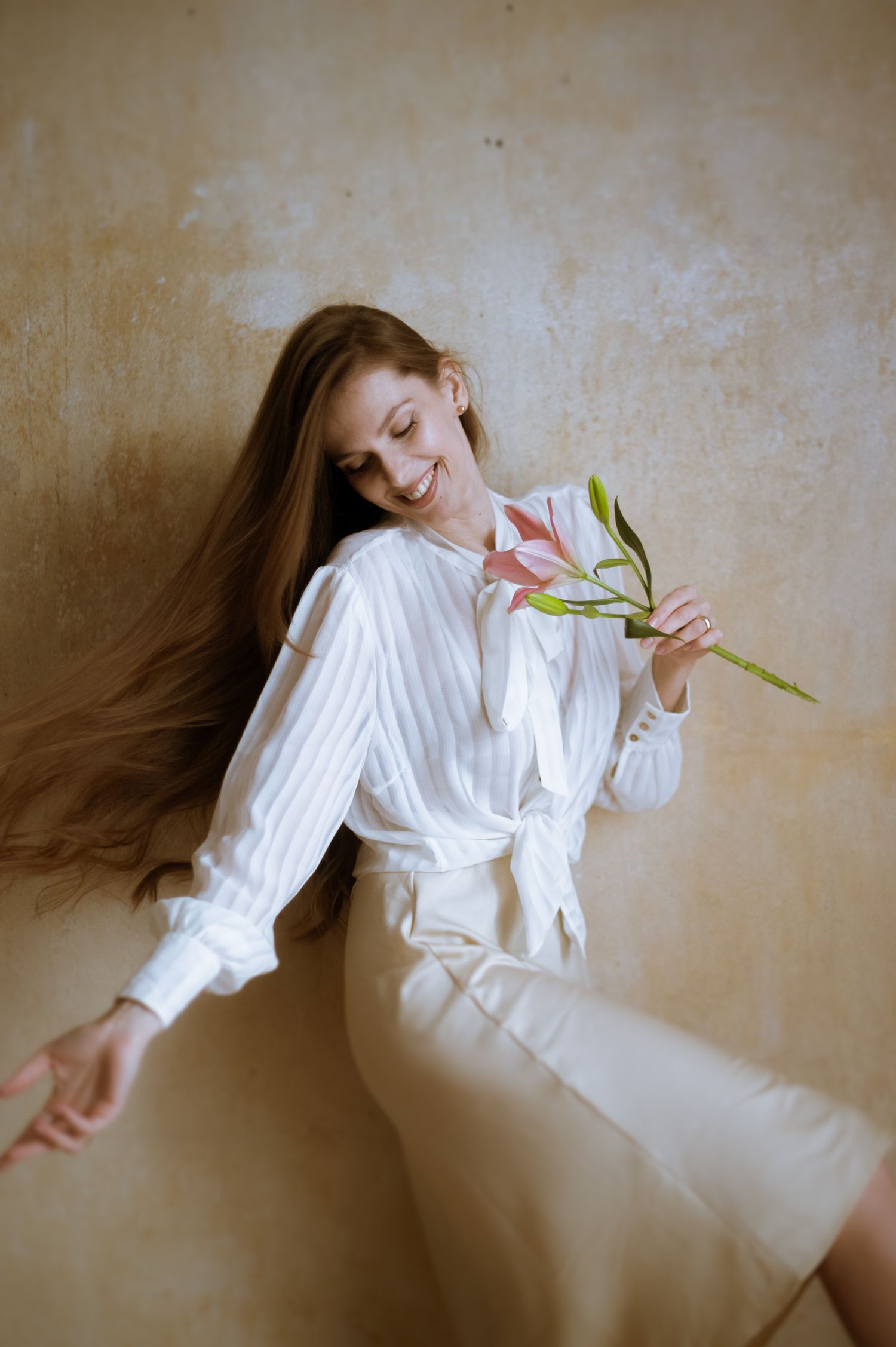A person in a white button-down shirt and dark pants poses expressively in a series of artistic indoor portraits.