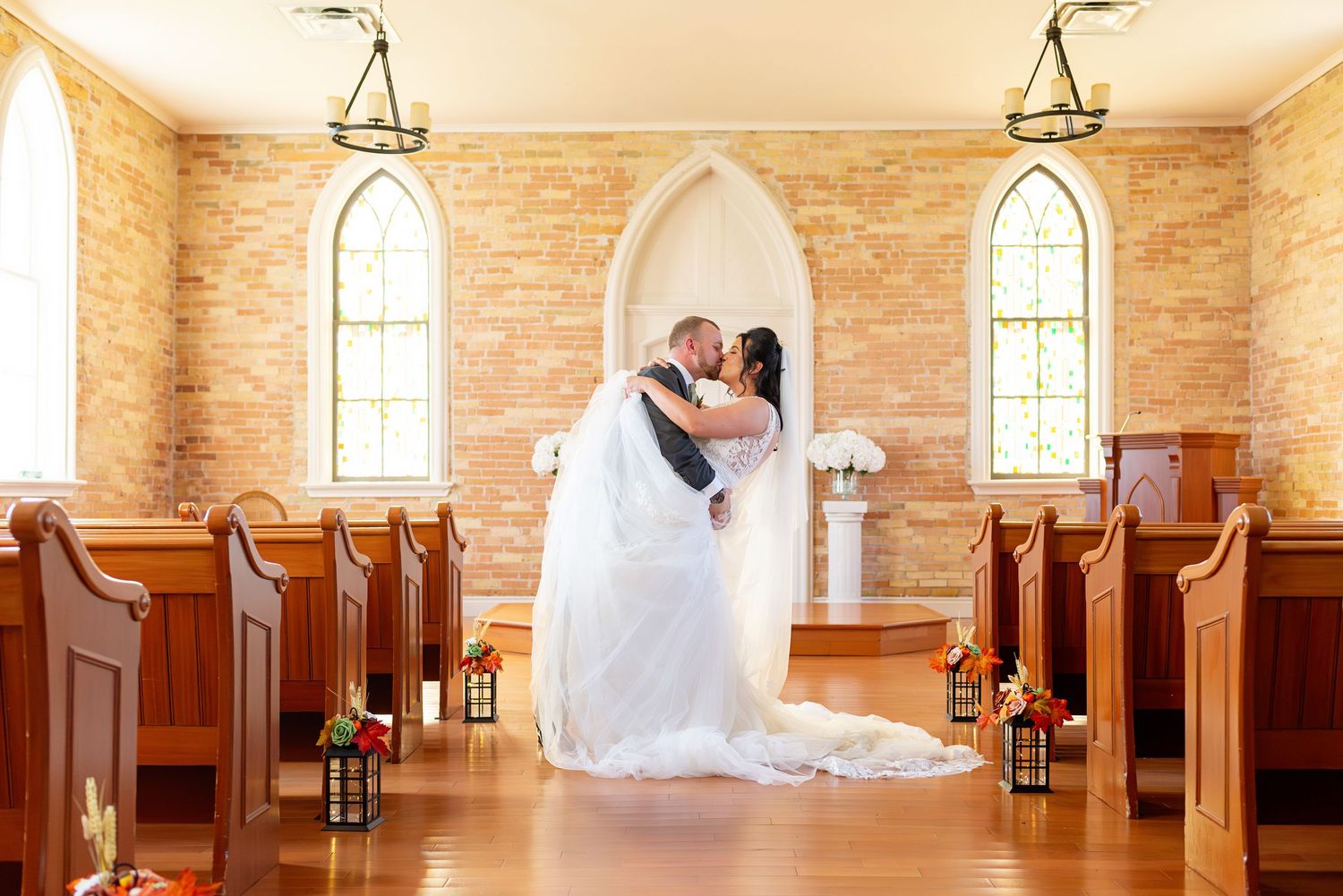 A romantic wedding ceremony moment inside a historic chapel with arched windows at the Rose Chapel.