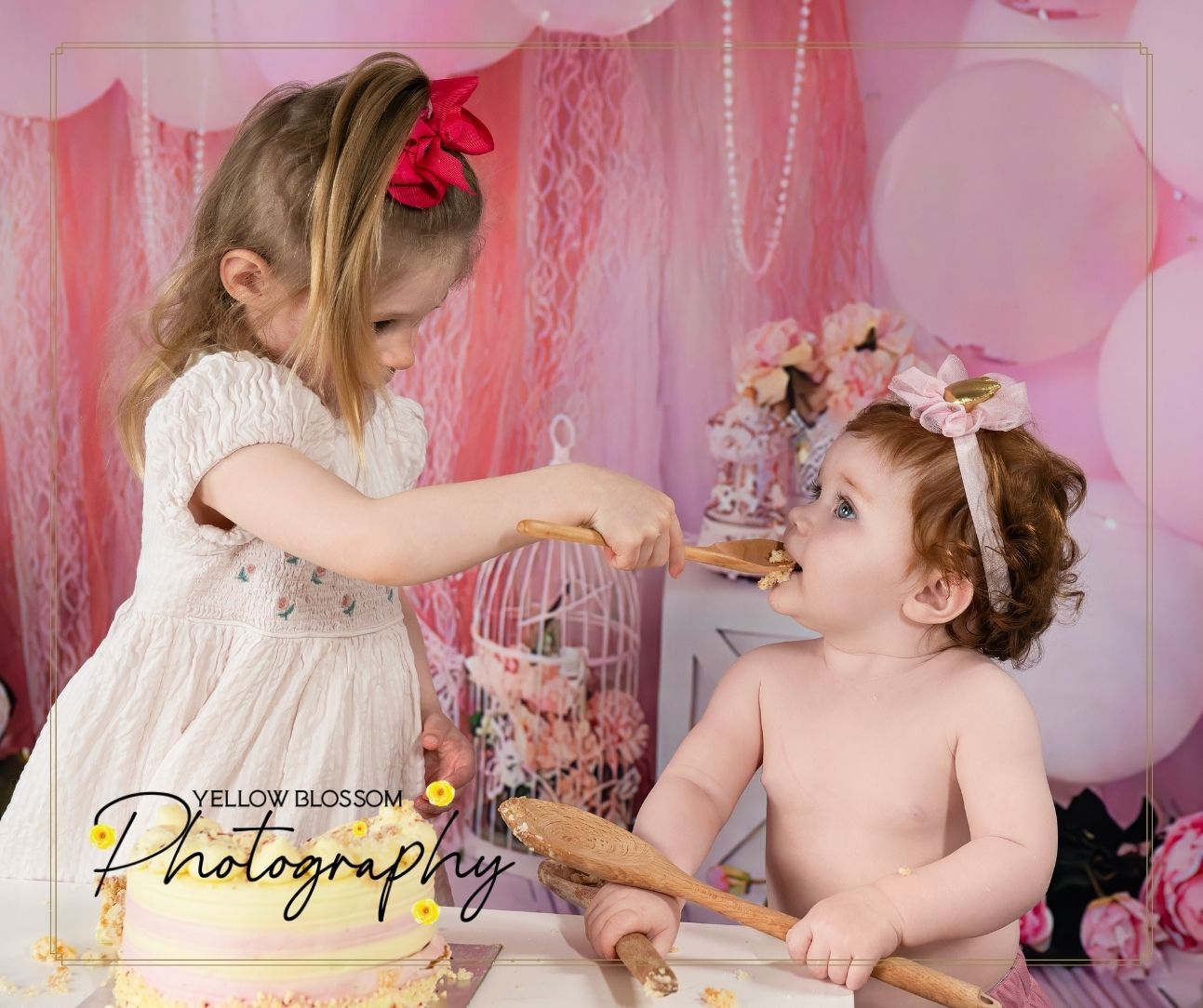 Two children in a pink decorated room playing dress up with birdcage and lace decorations.