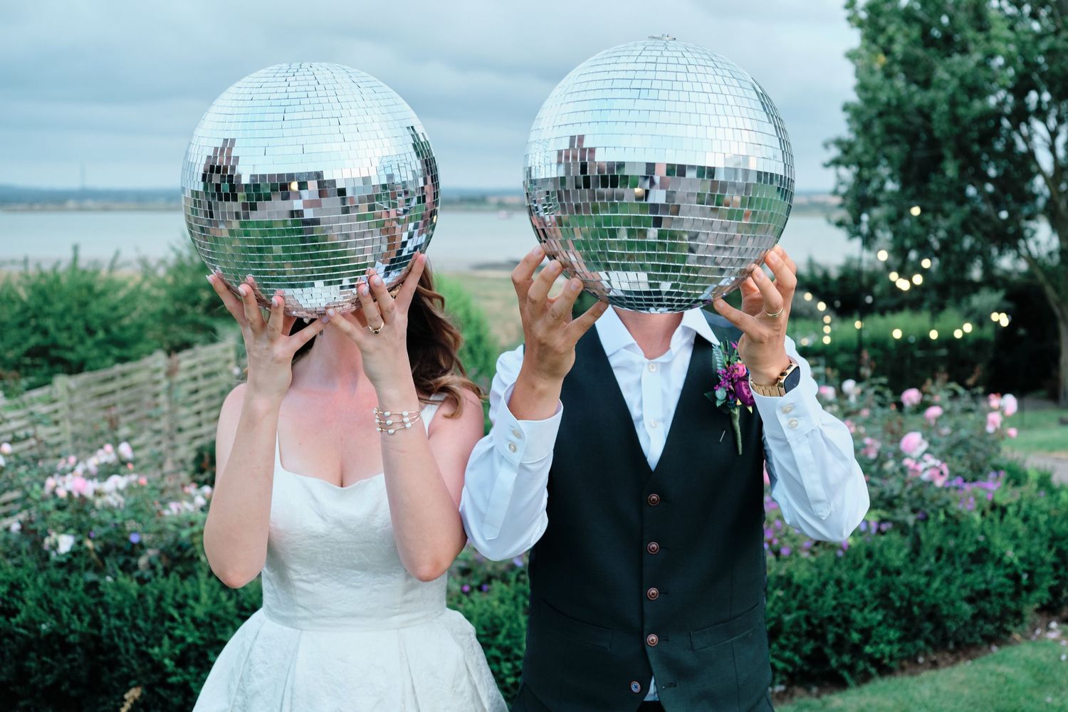 A cluster of people dance and throw paper or confetti in the air during an outdoor celebration at The Ferry House.