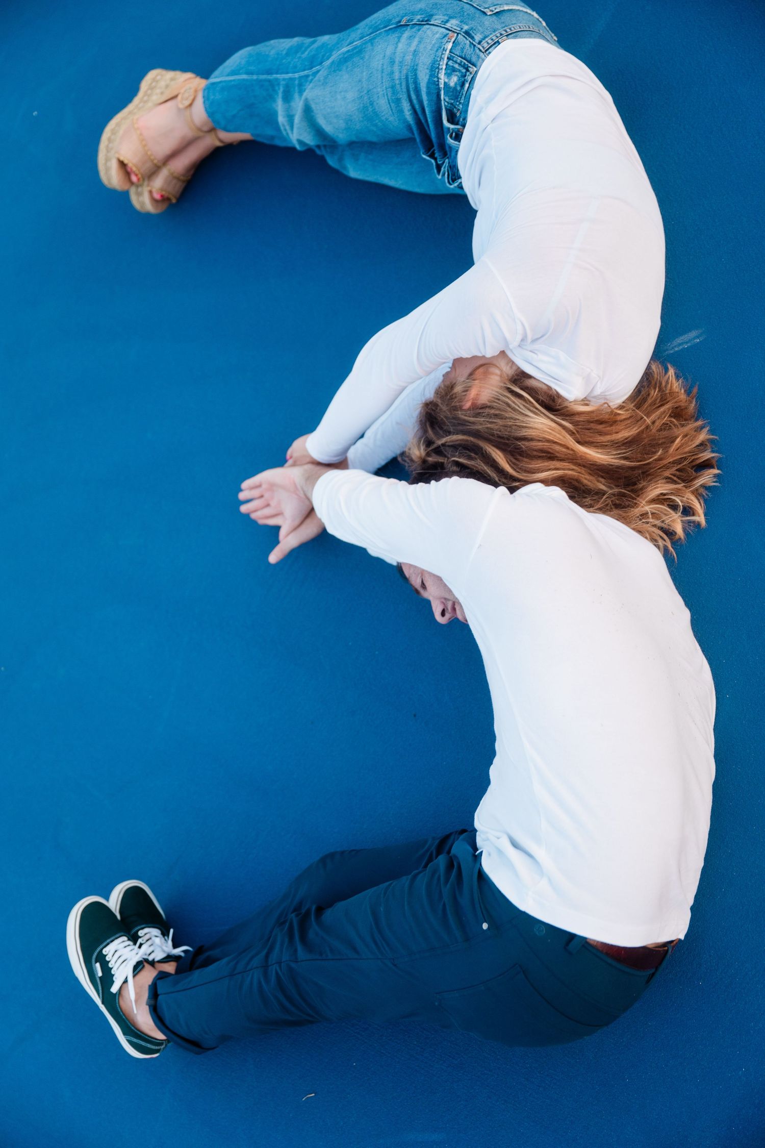 A person in white shirt and blue jeans performs a dynamic dance move against a vibrant blue background.