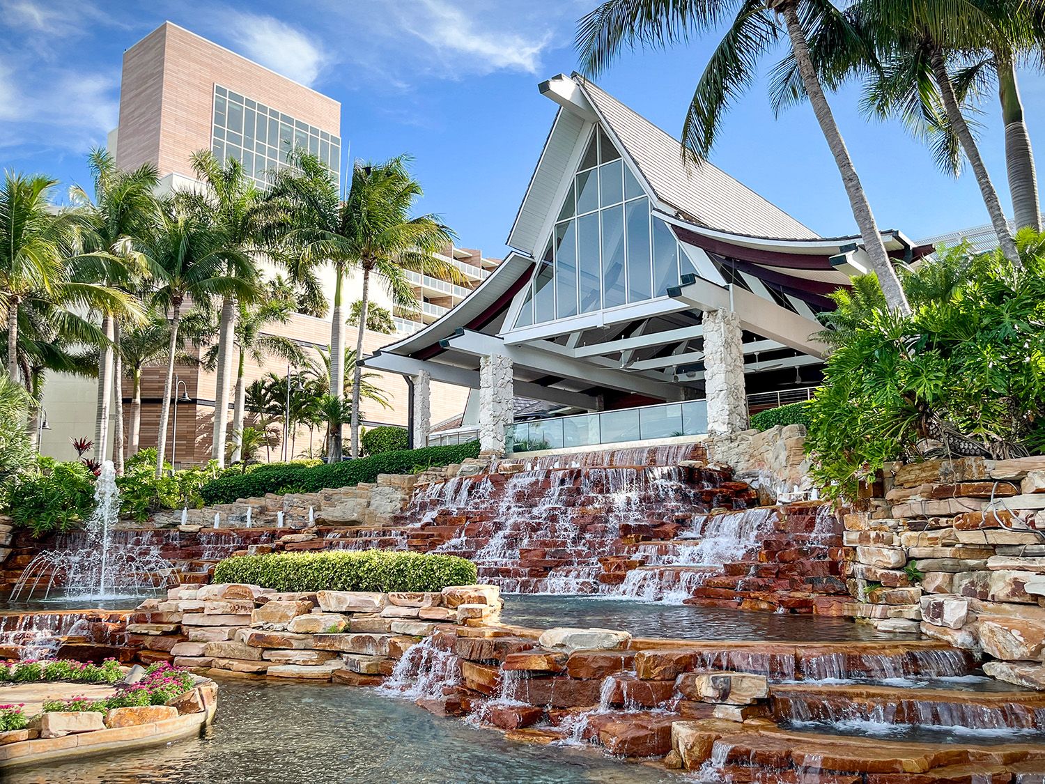 Marco Island JW Marriott entrance with cascading waterfall feature surrounded by tropical palm trees and stone landscaping in Florida.