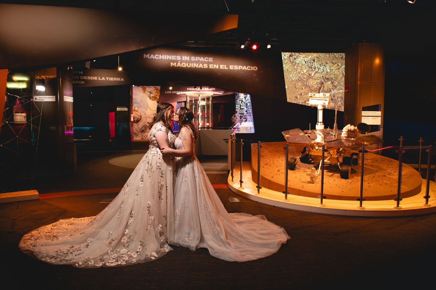 Museum exhibits display historical artifacts and information panels in a dimly lit gallery space with spotlights.