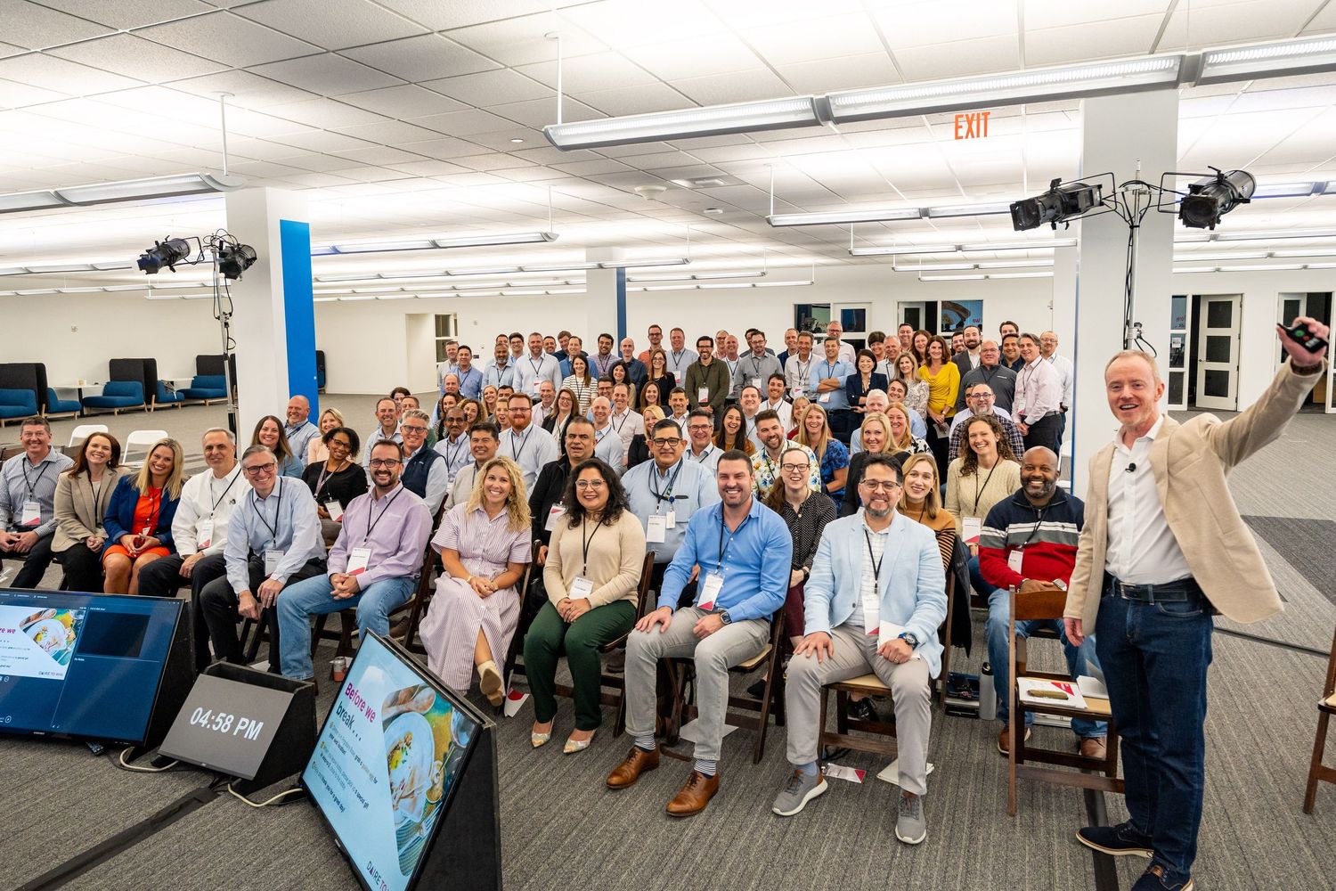 A panoramic view of a large gathering of people seated in rows during an indoor corporate event or meeting.