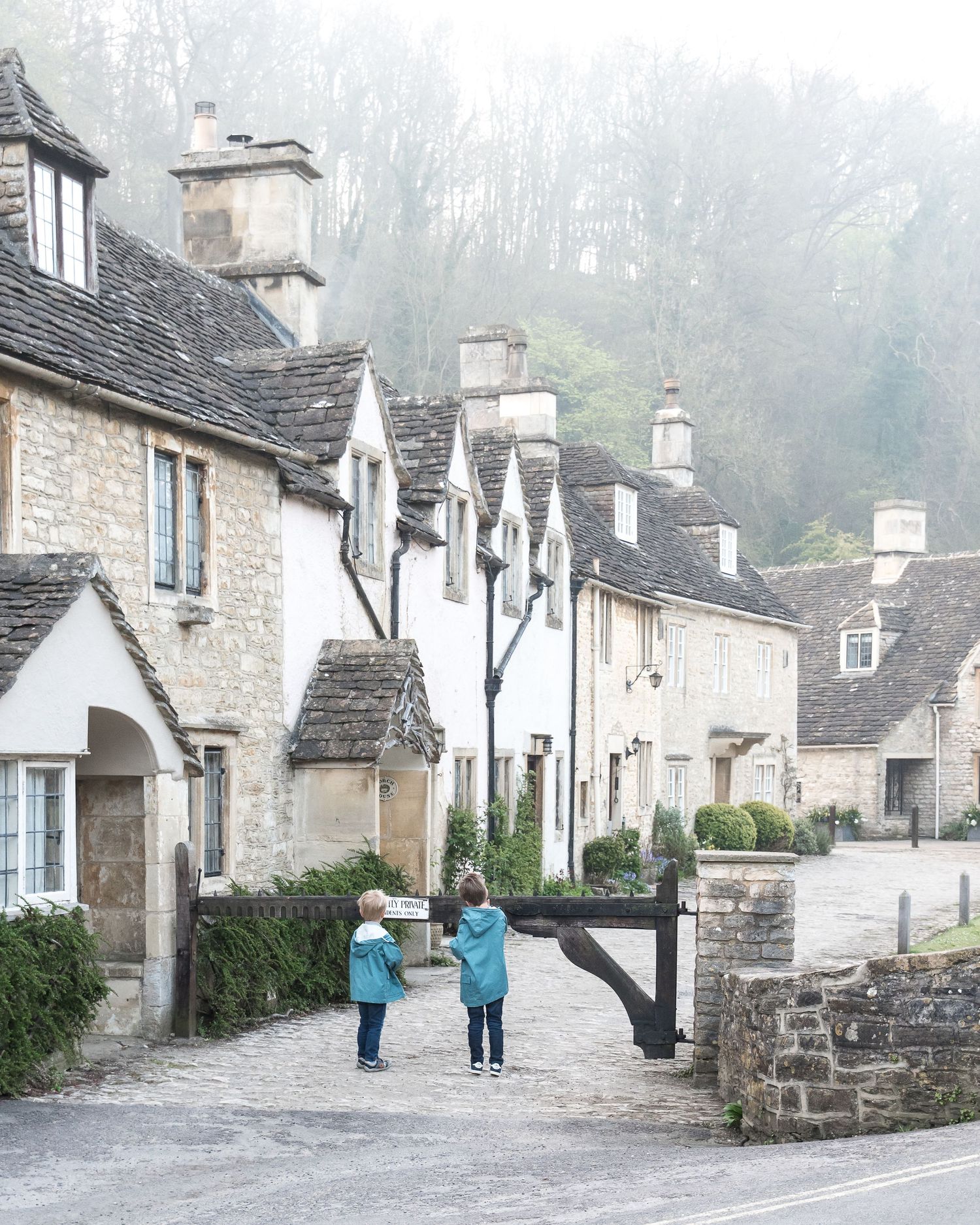 Misty view of traditional stone cottages along a quaint village street.