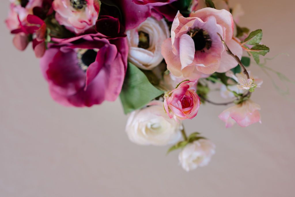 A rustic wooden wedding arch decorated with cascading white and burgundy flowers in an outdoor garden setting.