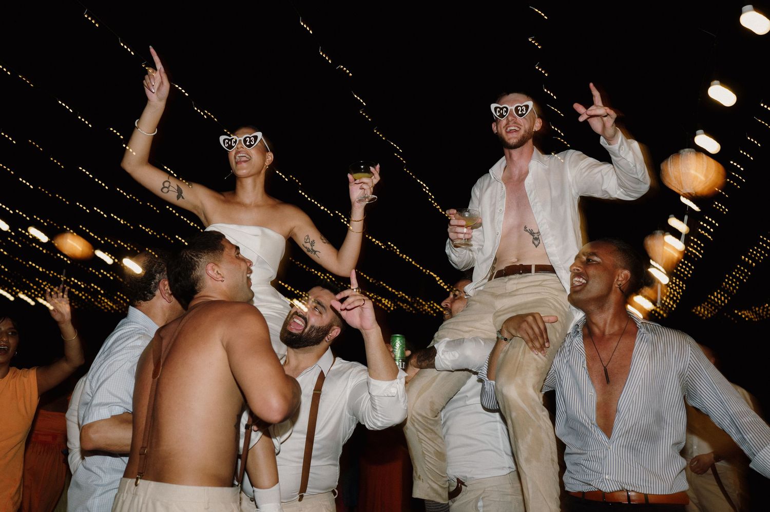 Group of party goers dancing energetically at a club with strobe lights illuminating the dark space.