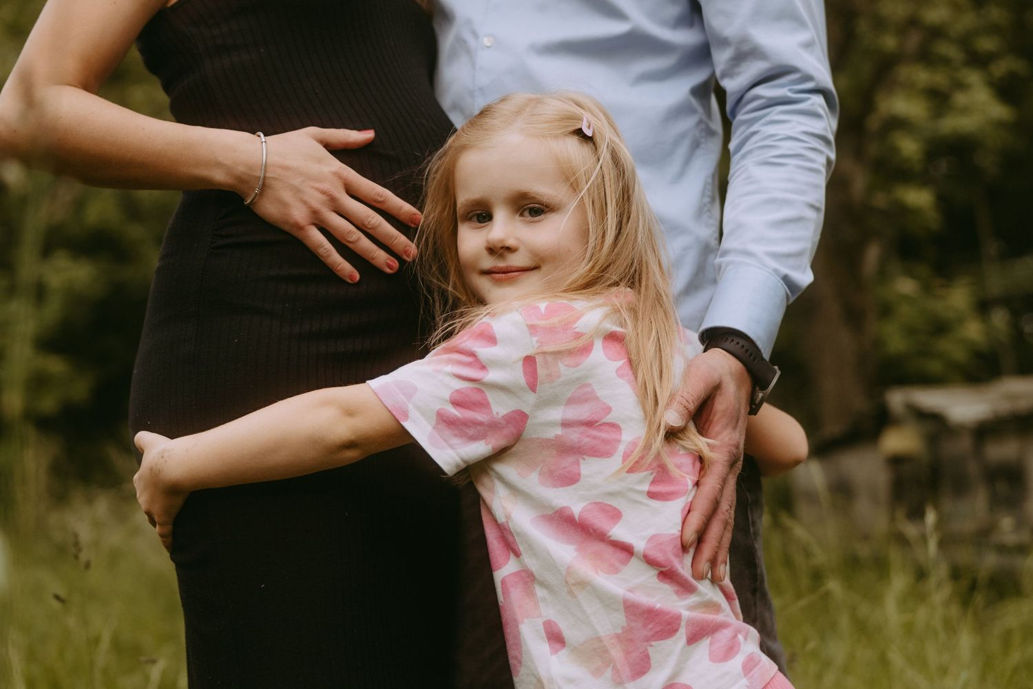 Candid family moment captured in a sunlit meadow with soft natural lighting.