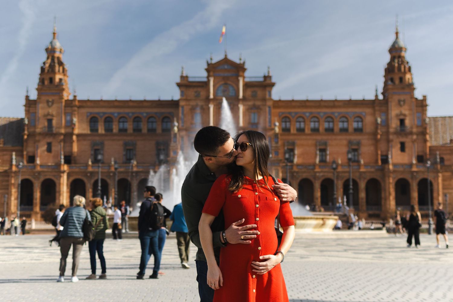 People enjoying a sunny day at Plaza de Espana in Seville, Spain with its iconic architecture and fountains in view.