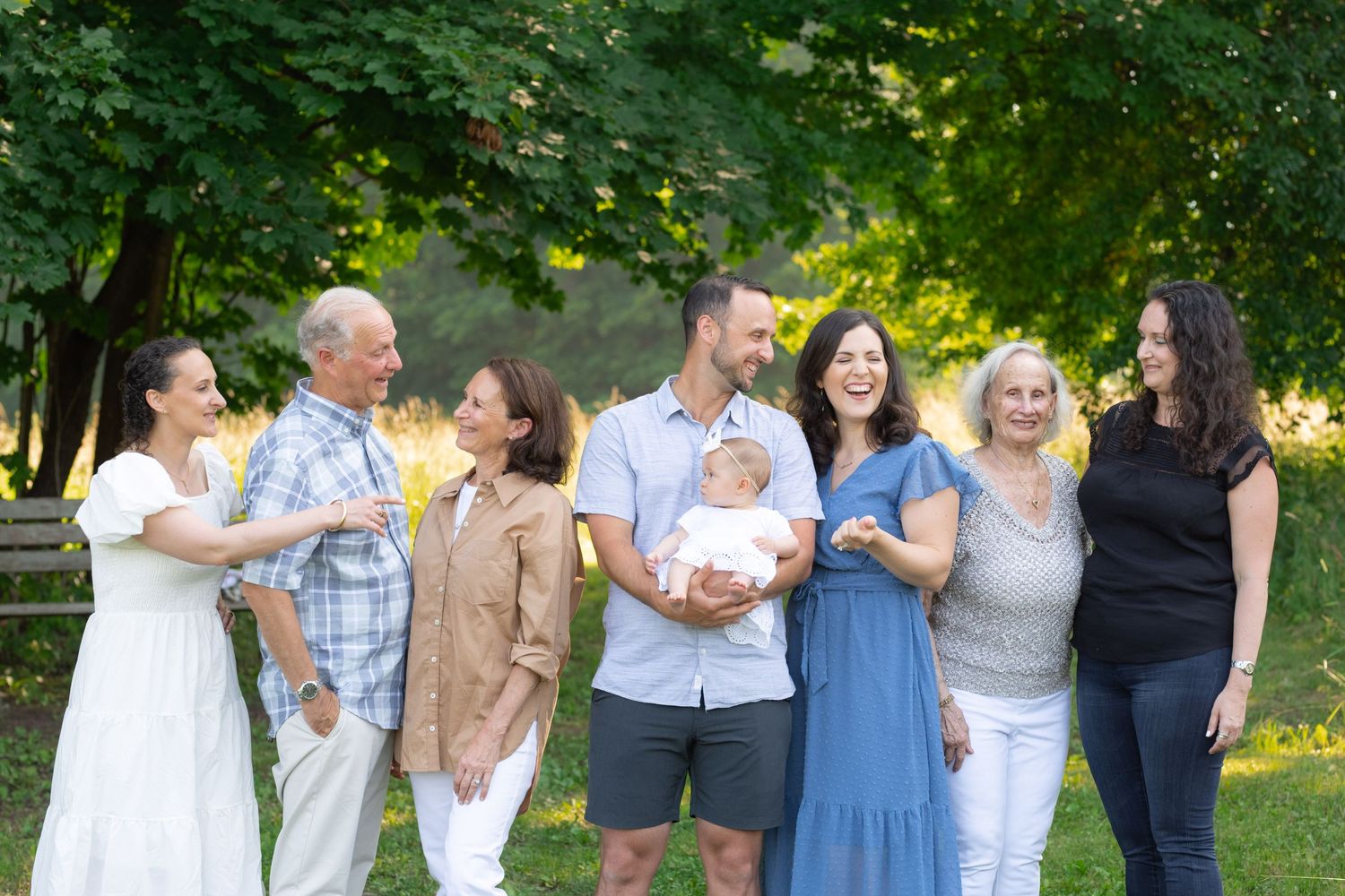 Group gathered outdoors for a family photo under green summer trees.