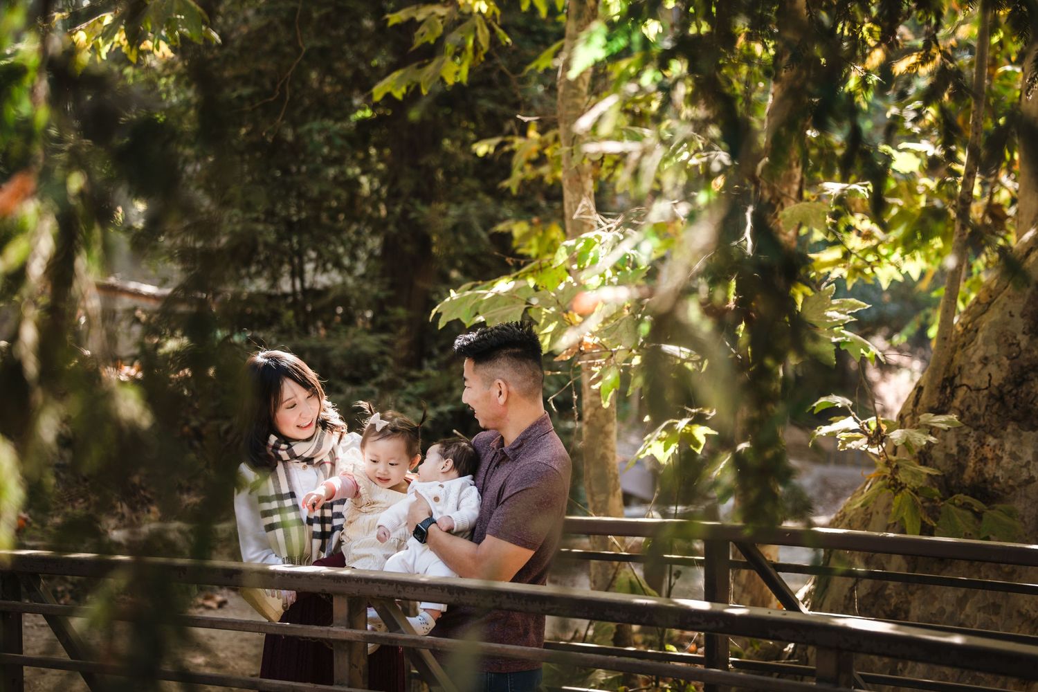 A family enjoys a peaceful moment together on a bench surrounded by lush greenery in a garden setting.