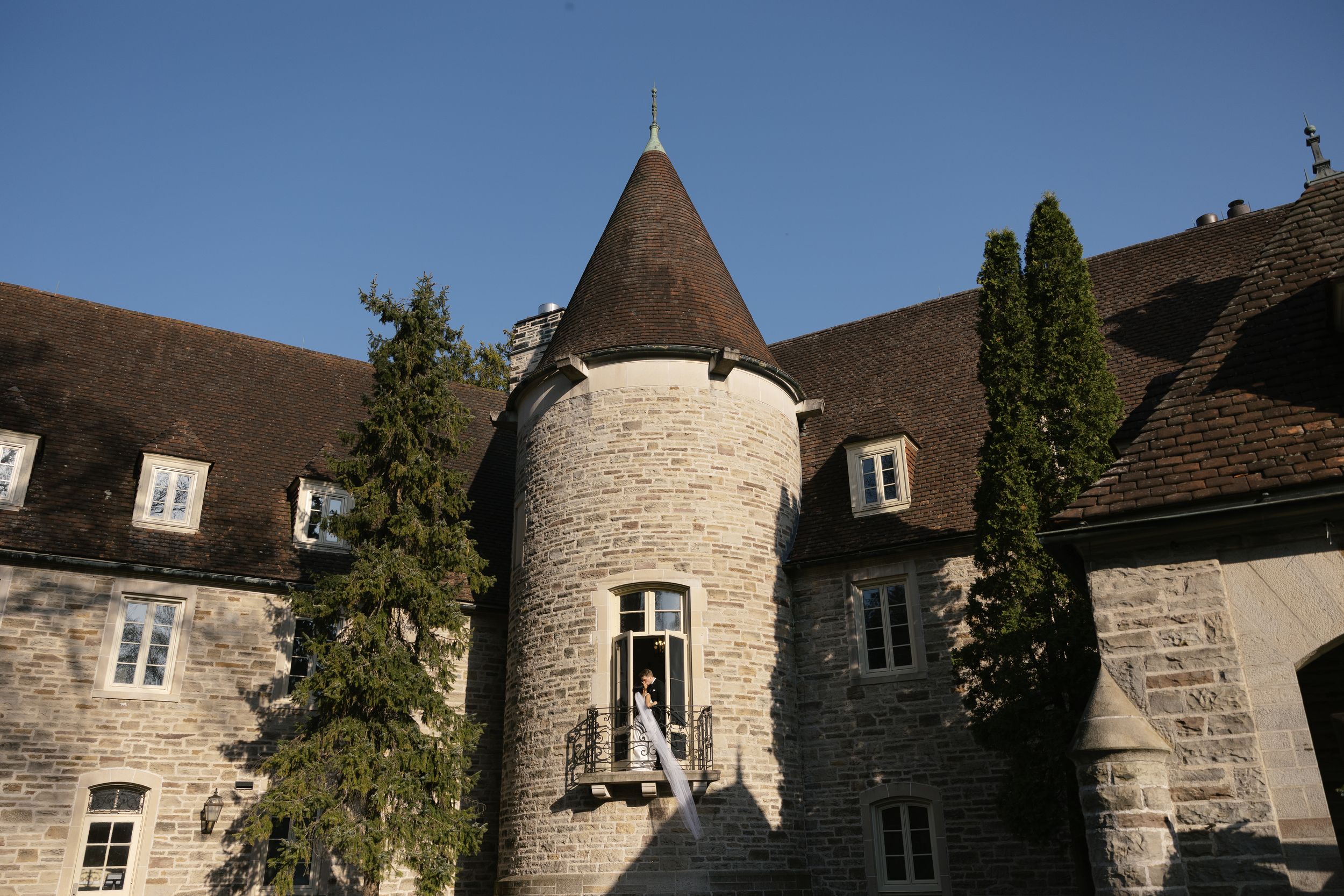 Historic stone castle with circular tower and turret features white windows against a medieval architectural backdrop.