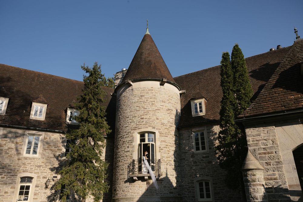 Historic stone castle with circular tower and turret features white windows against a medieval architectural backdrop.
