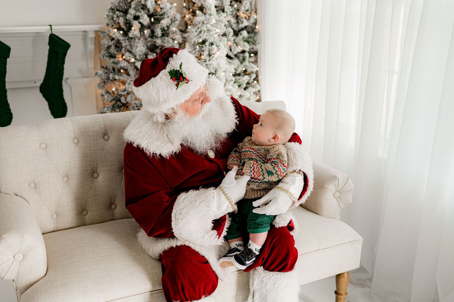 Holiday scene with traditional red-suited figure seated on beige couch near decorated tree.