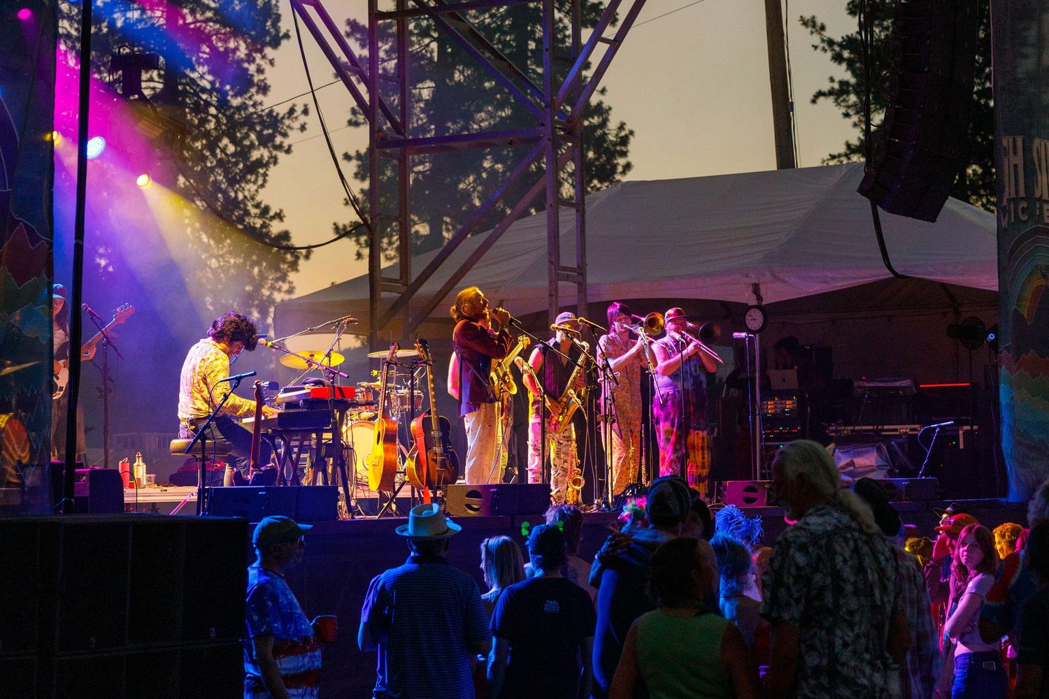 Band performs on stage with colorful purple lighting and fog effects at night.
