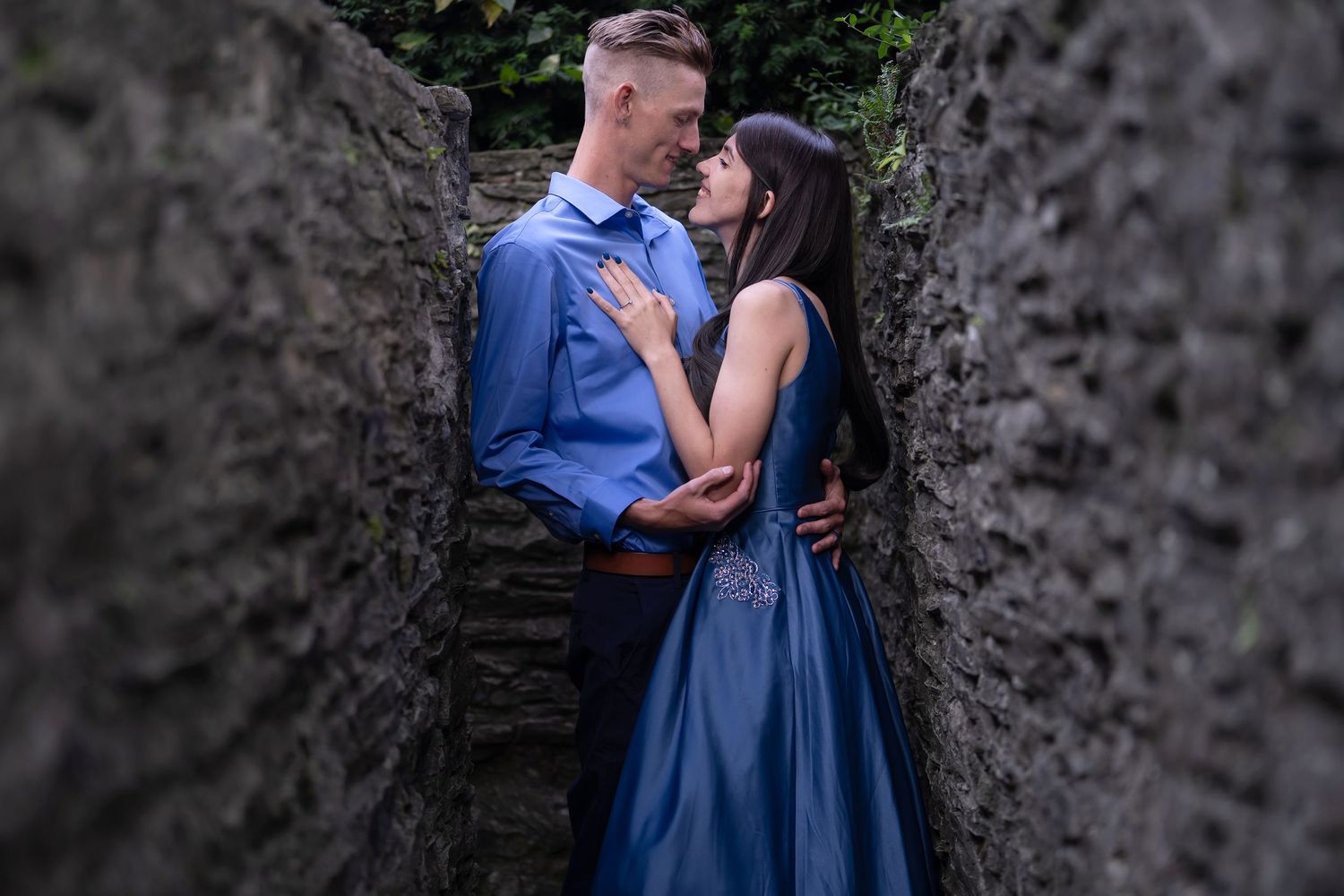 Couple embraces in golden wheat field during sunset photoshoot.