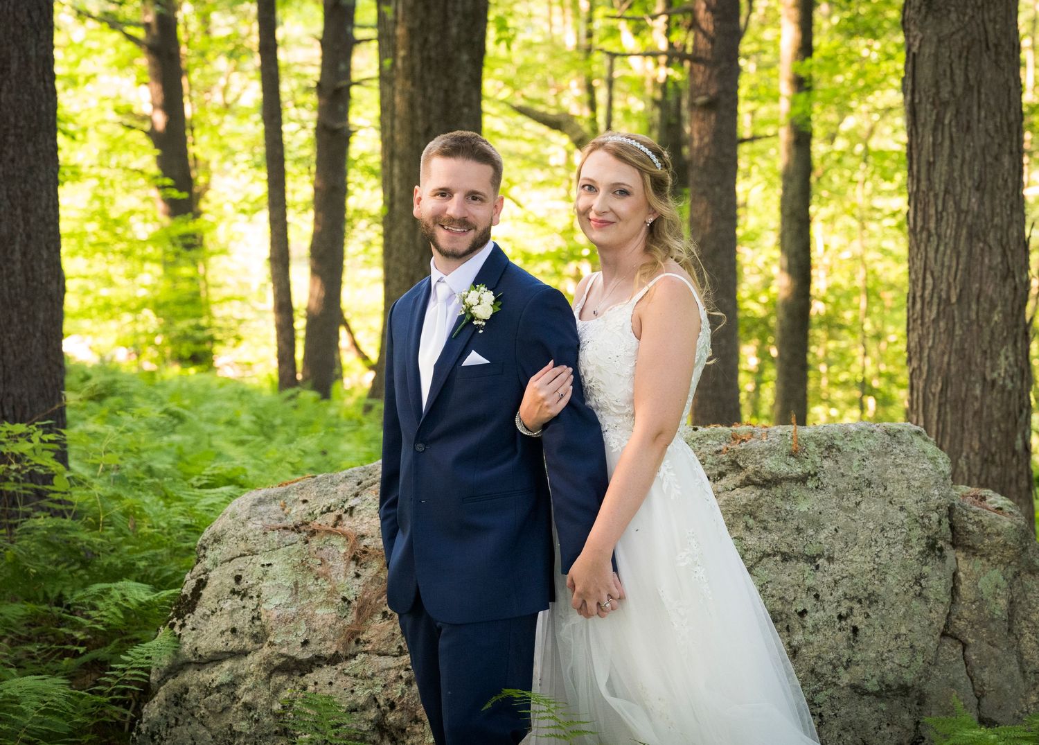 Newlyweds share an intimate moment outdoors with autumn foliage and rustic architecture in background.