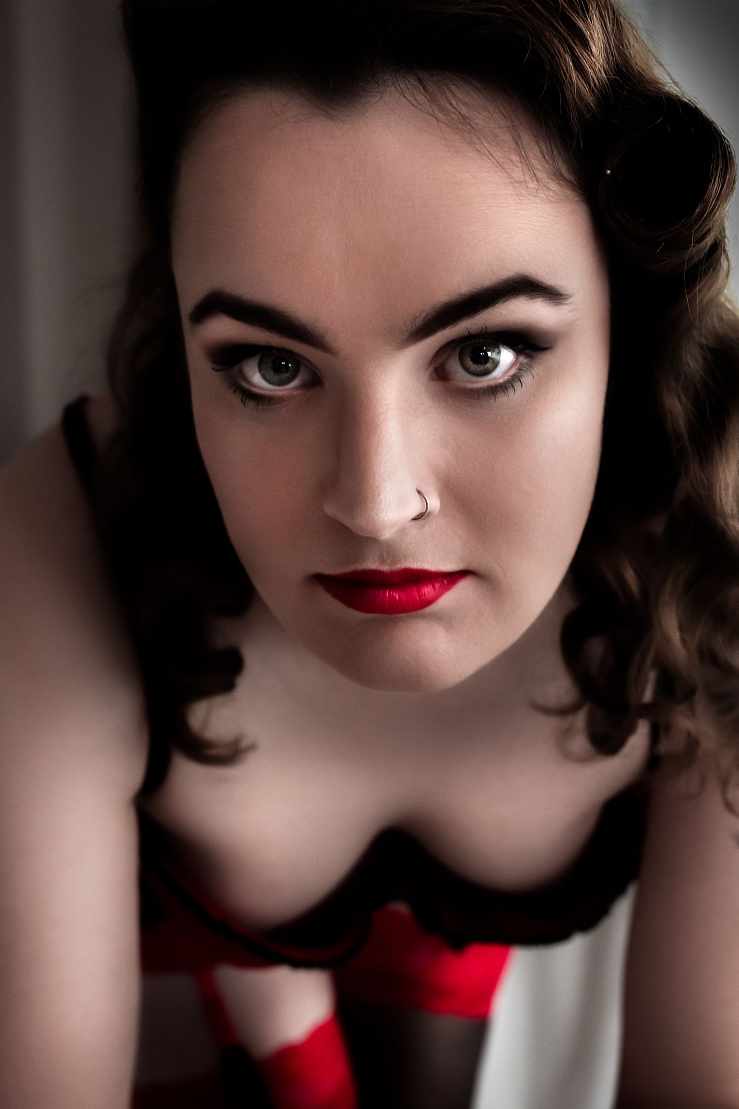 Classic pin-up style beauty portrait with red lipstick and vintage hair styling.