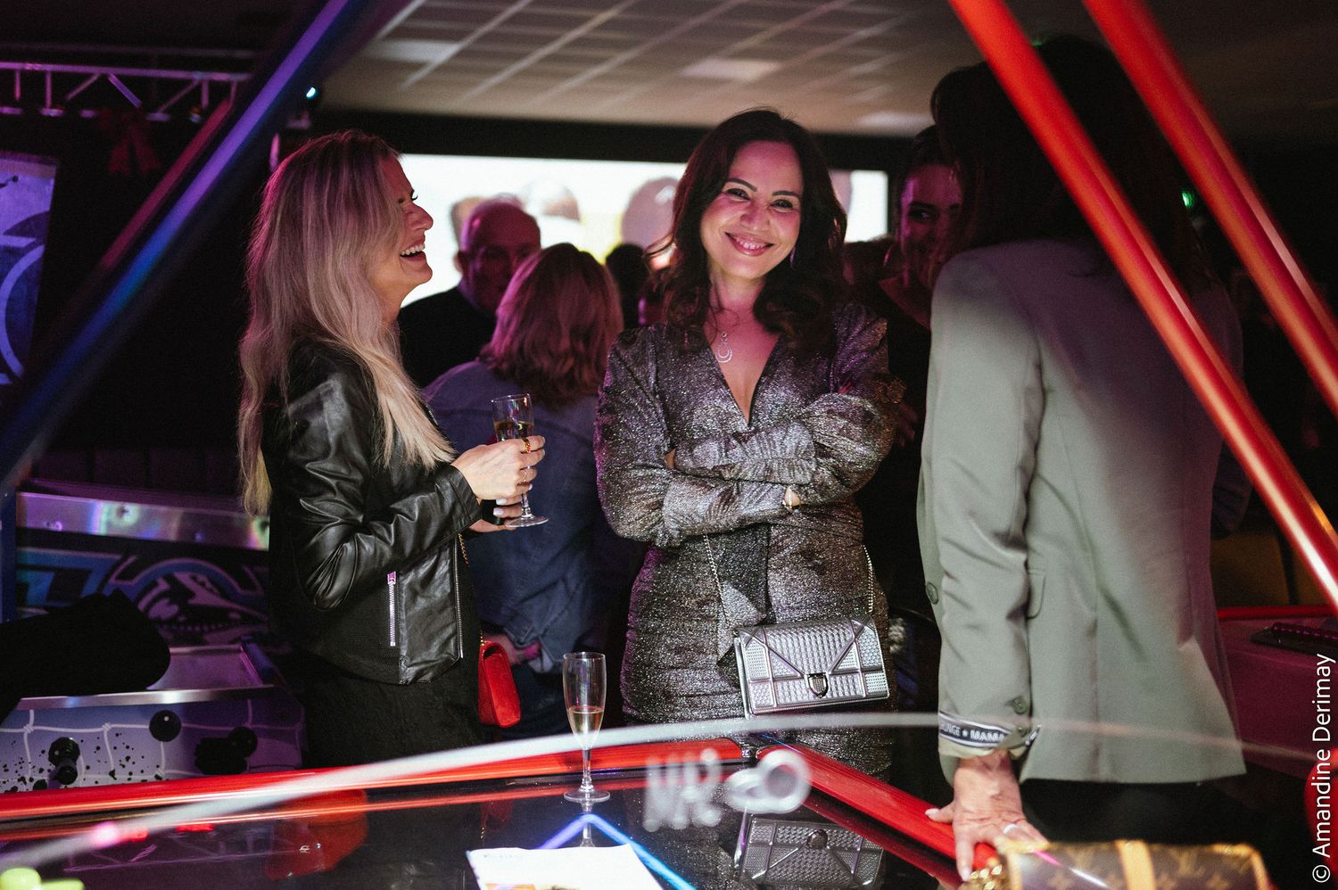 Groupe de femmes en pleine discussion autour d’une table de jeu, dans une salle animée lors d’un événement d’entreprise.