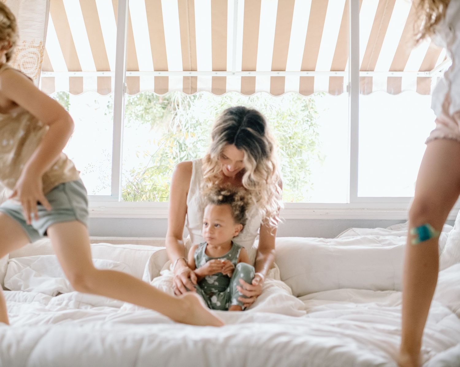 Playful moment on a cozy bed under striped awning.