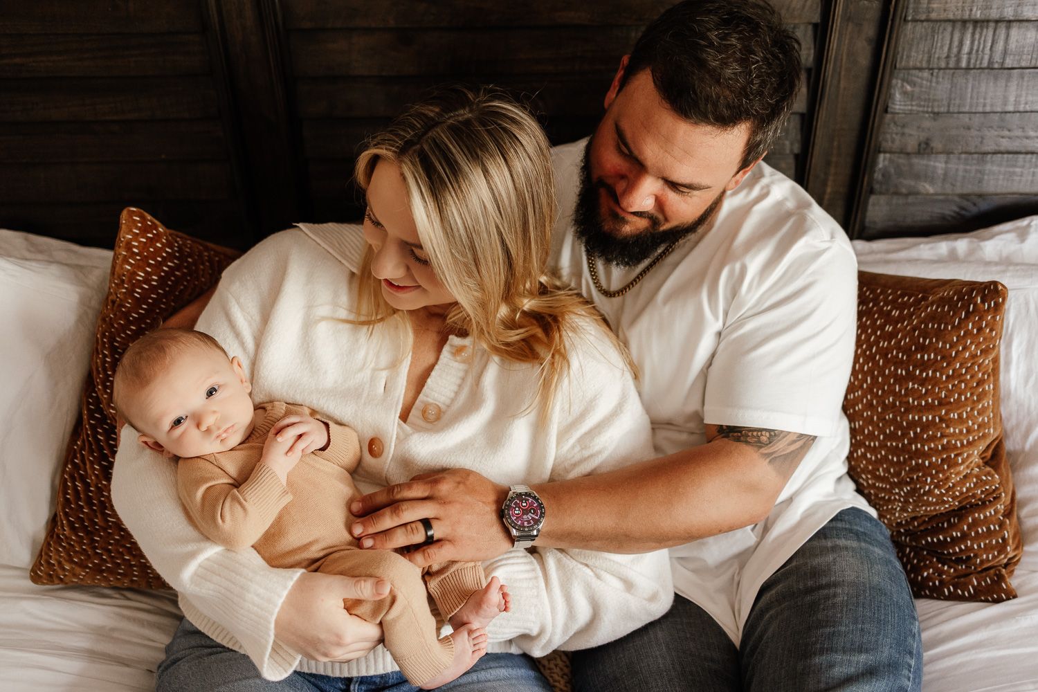A newborn baby snuggles in his parents arms during a newborn photoshoot in Morgan Hill