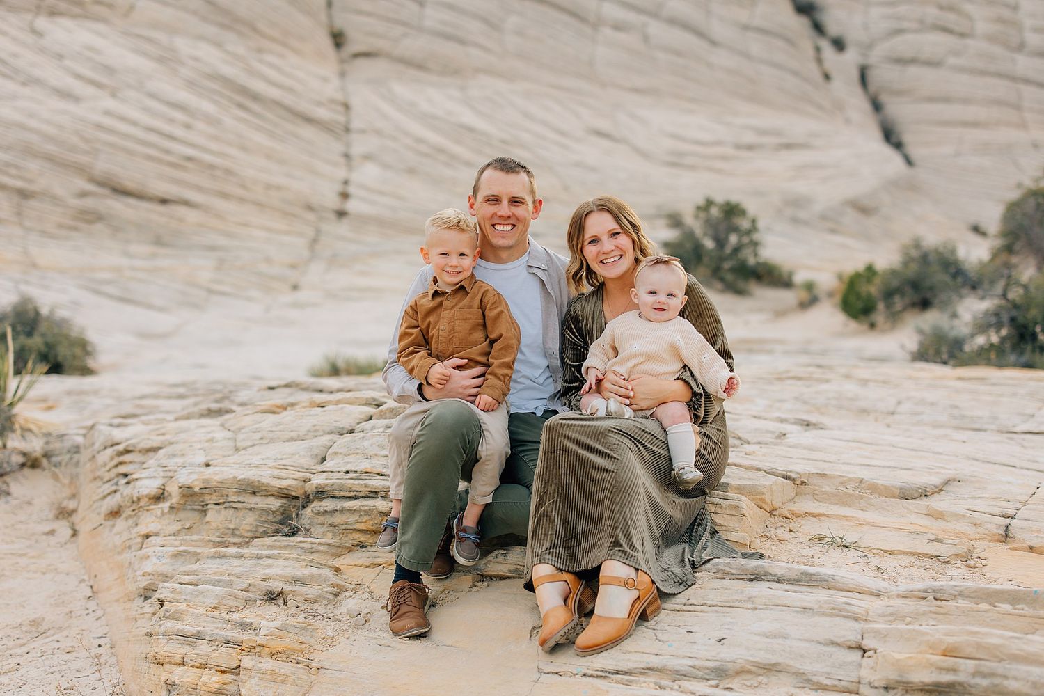 A happy family shares joyful moments together while sitting and laughing outdoors in casual attire.