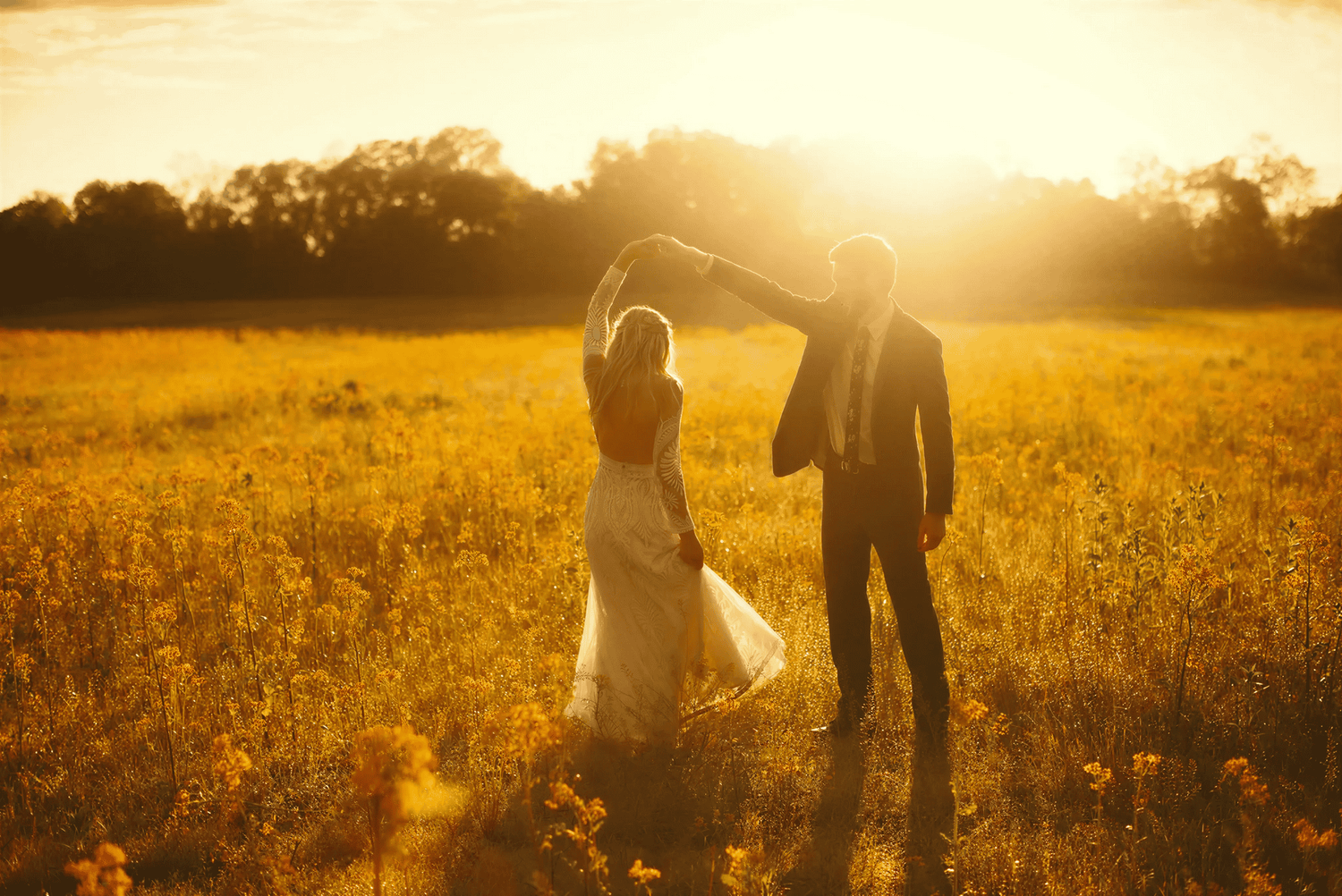 Beautiful couple dancing in a field during golden hour