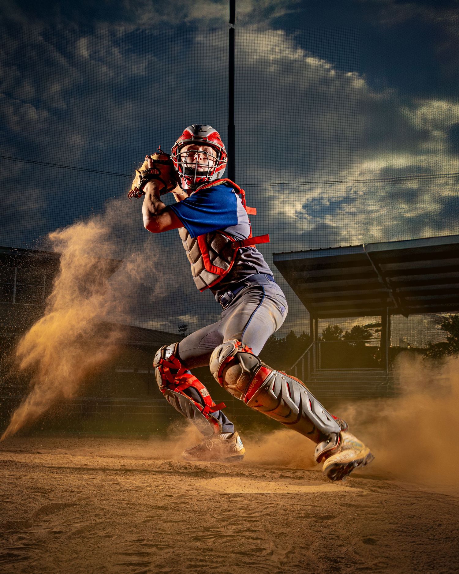 Baseball player slides into base creating a cloud of dust during intense game action at night.
